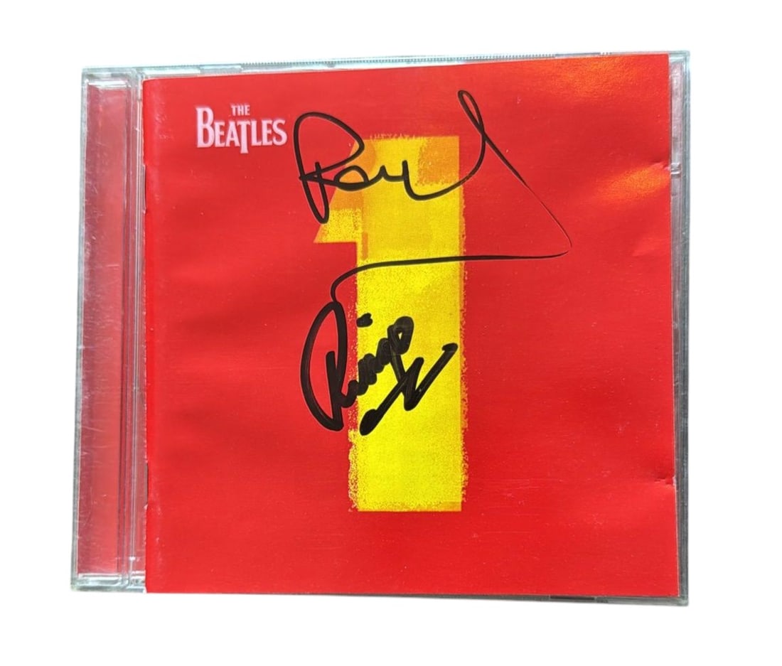 The Beatles Signed CD: This lot is a CD (Beatles 1), autographed on the front of the CD sleeve by Ringo Starr and Paul McCartney of The Beatles. Item comes with third-party authentication and affixed tamper-proof holographi
