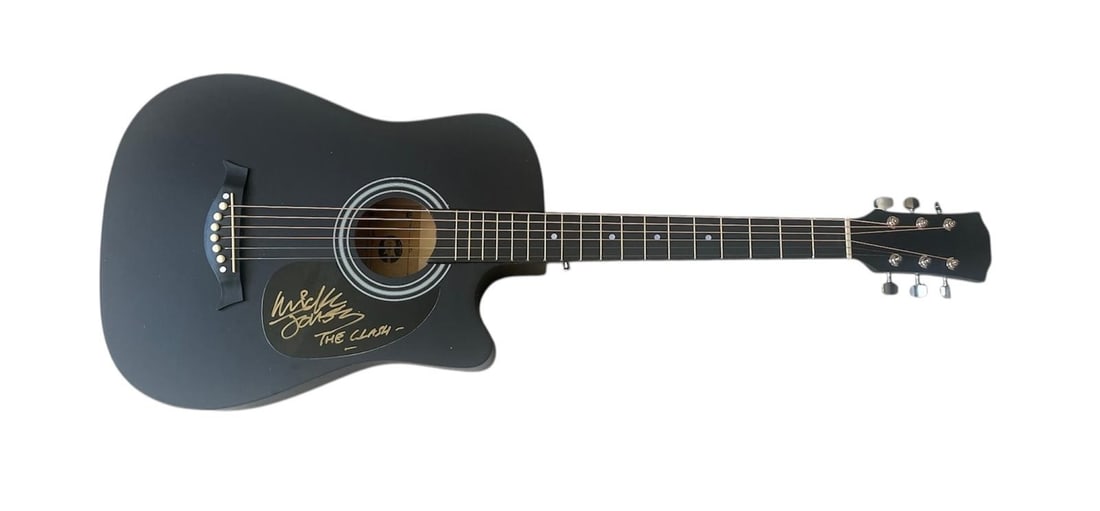 The Clash Mick Jones Signed Acoustic Guitar: This lot is an acoustic guitar, autographed on the plate by Mick Jones of The Clash. Item comes with third-party authentication and affixed tamper-proof holographic QR sticker leading to item details