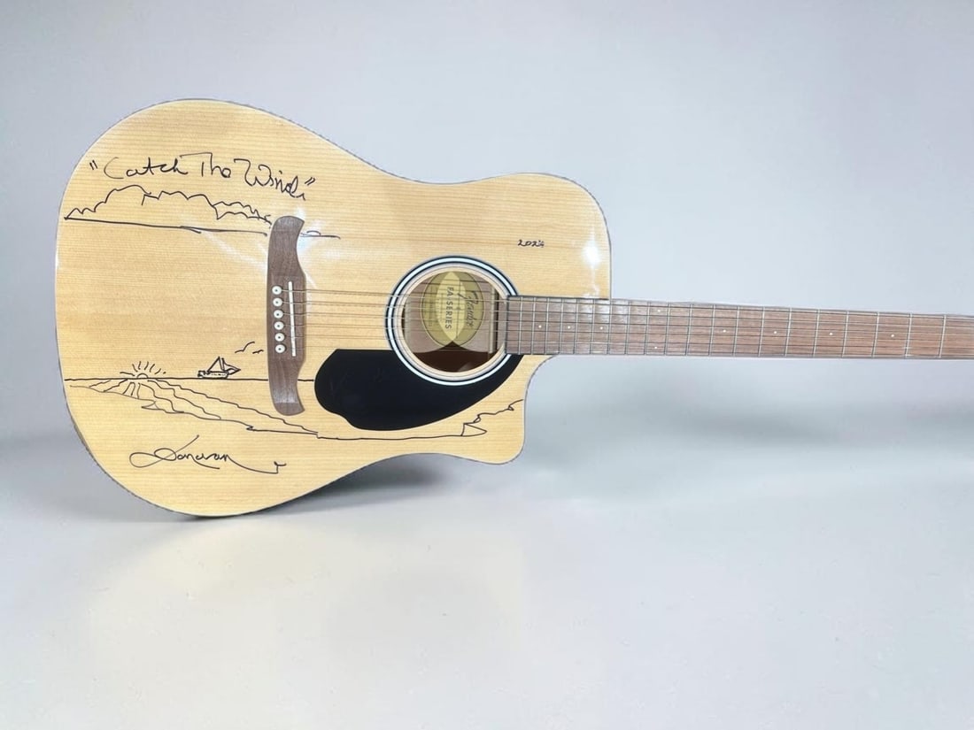 Donovan Signed Acoustic Fender Squier Guitar: This lot is an acoustic Fender Squier Guitar, autographed on the body by Donovan. Item comes with Catch The Wind Artwork. Items comes with exact photographs from time of signing. Item comes with