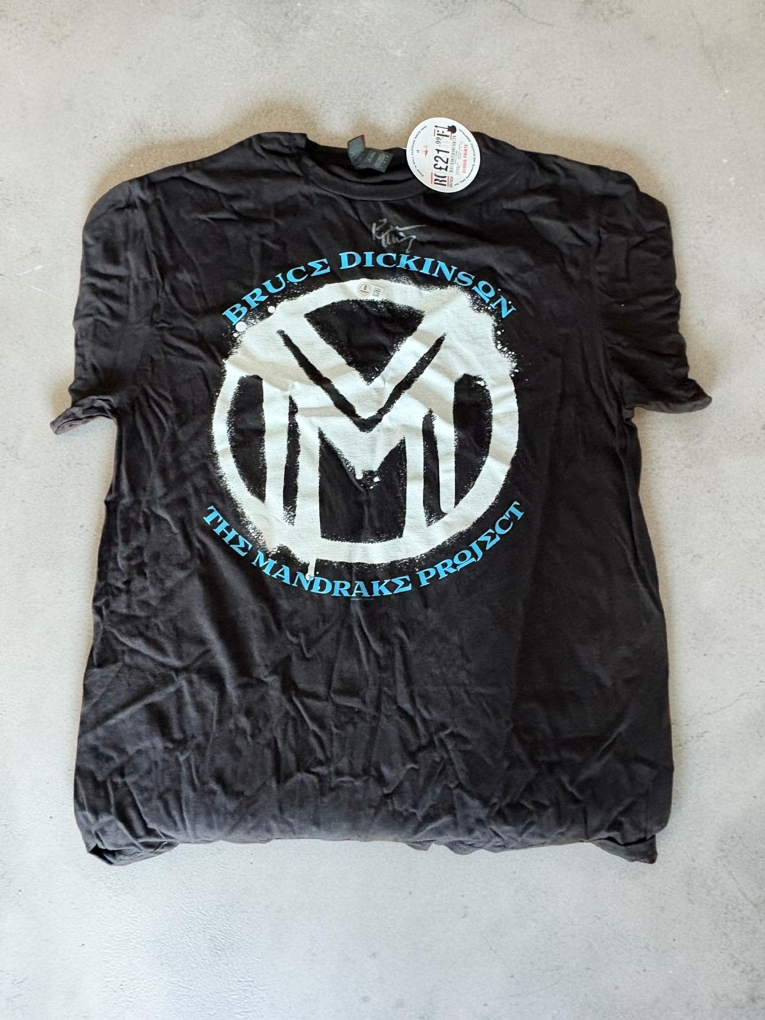 Bruce Dickinson Iron Maiden Signed T-Shirt The Mandrake Project Beckett BAS Authenticated: This lot is a T-Shirt, autographed by Bruce Dickinson of Iron Maiden. Item comes with third party authentication including interactive QR code, item details and scoring. Item comes with Beckett BAS