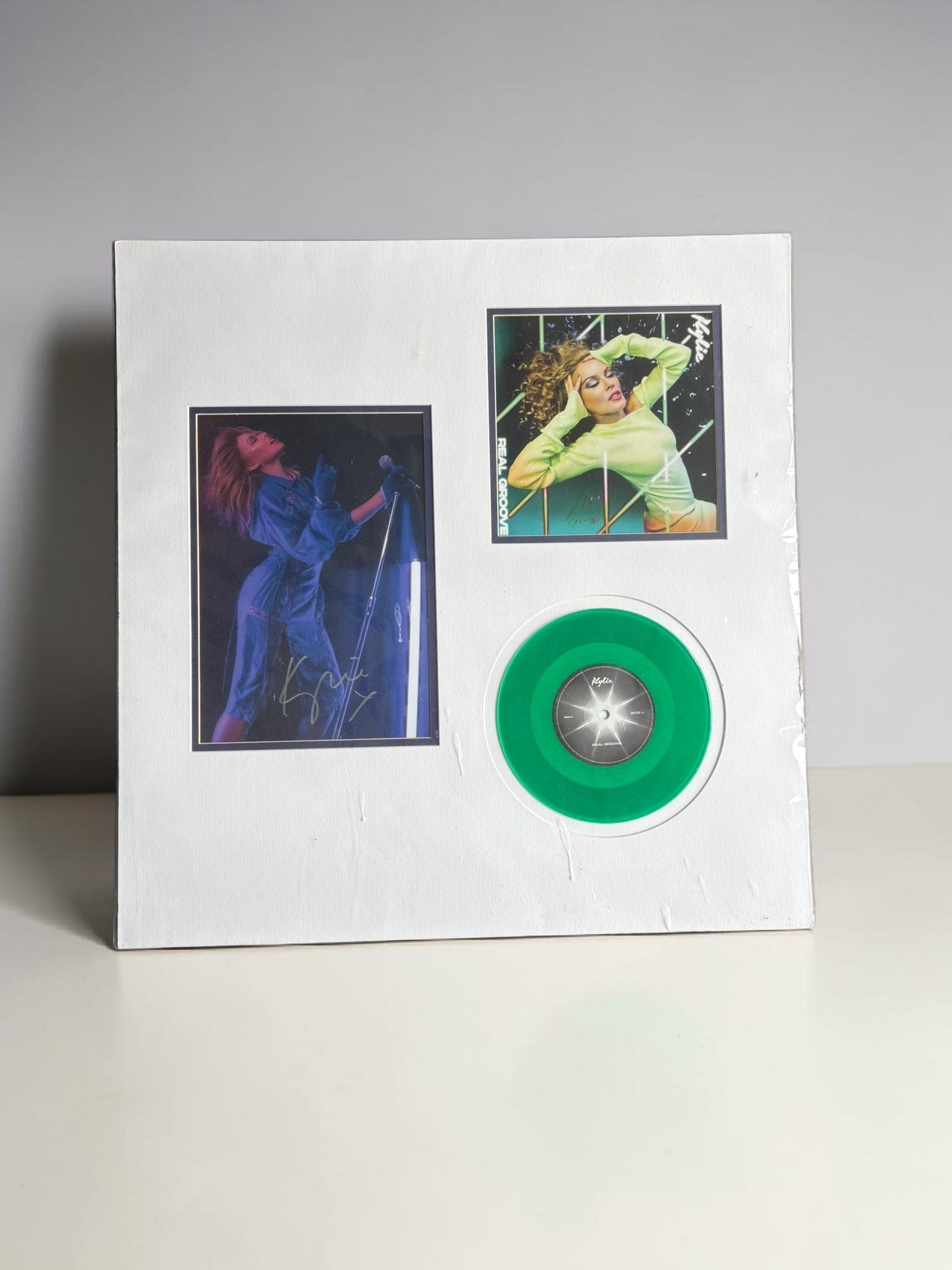 Kylie Minougue Signed Mounted Display: This lot is a mounted display, consisting of a vinyl 45 (Real Groove) and a 10x8" photograph. Photograph is autographed by kylie Minogue. Item comes with third party authentication including interacti