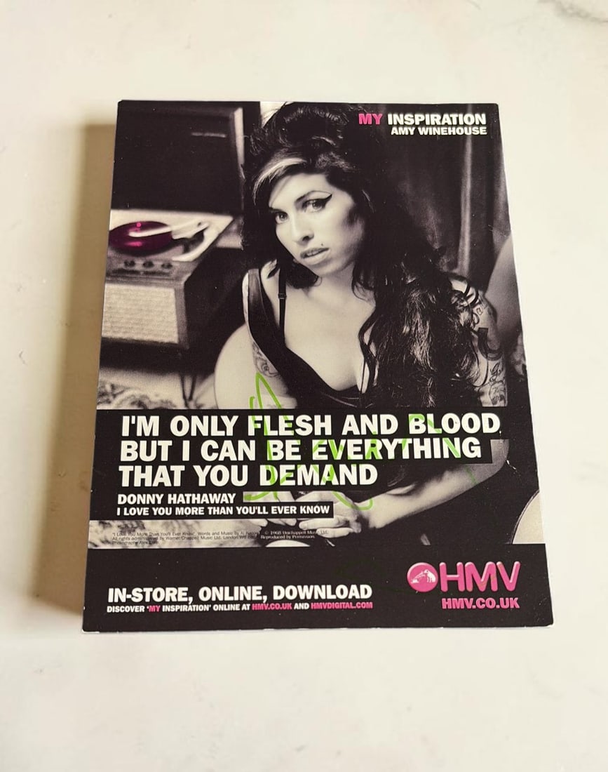 Amy Winehouse Signed 2007 HMV Promotional Card: This lot is a promotional card (HMV 2007), autographed on the front of the promotional card in green sharpie pen by Amy Winehouse. Item comes with third party authentication including interactive QR c