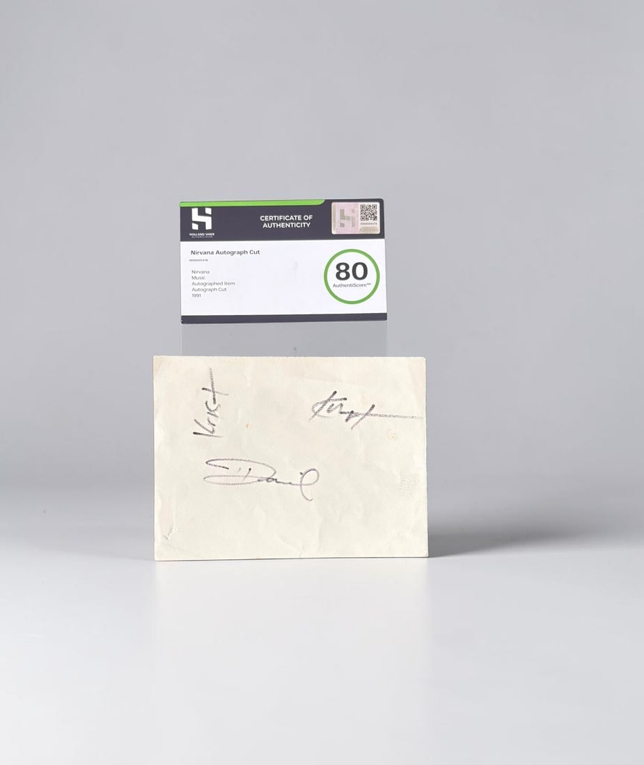 Nirvana Signed Autograph Cut: This lot is an autograph cut from 1991, autographed by Kurt Cobain, Dave Grohl and Krist Novoselic of Nirvana. Autographs are signed in black felt pen, authenticated by HSA with an authentiscore of 80