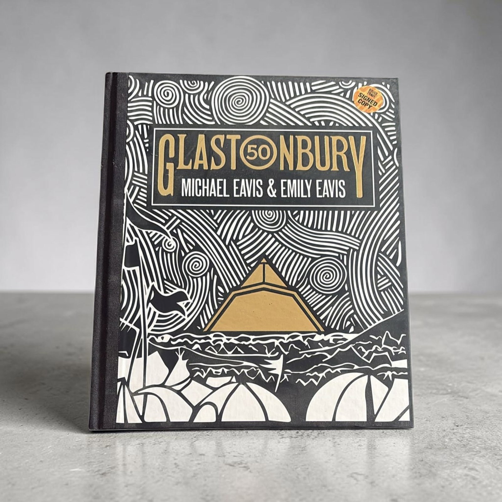 Glastonbury Signed Michael Eavis And Emily Eavis Hardback Commemorative Book: This lot is a hardback Glastonbury Commemorative book, autographed by Michael Eavis and Emily Eavis. If you wish to upgrade to a third party authentication with holographic QR code and item scoring, a