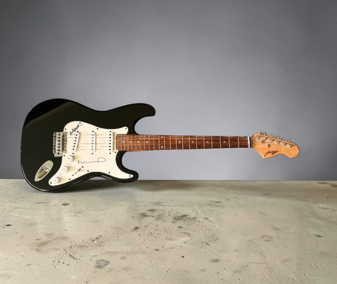 Oasis Signed Stratocaster Style Electric Guitar: This lot is a Stratocaster style electric guitar, autographed by Noel Gallagher and Andy Bell of Oasis. If you wish to upgrade to a third party authentication with holographic QR code and item