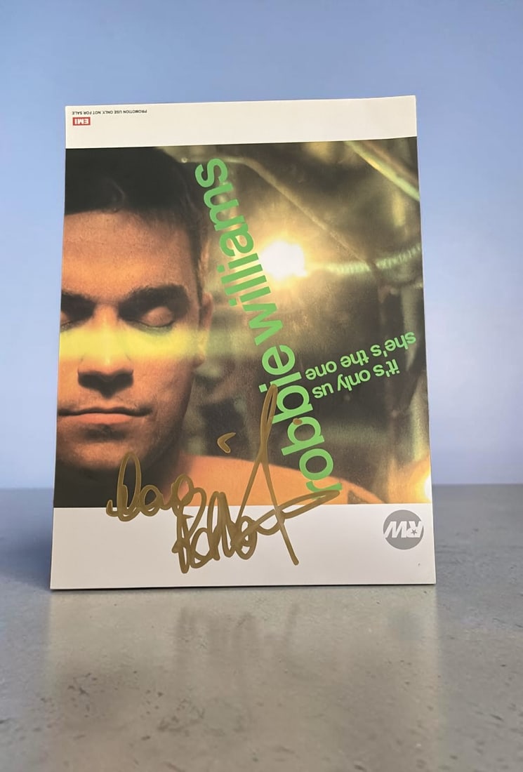Robbie williams Signed Official Promotional Card: This lot is a 10x8" official promotional card (It's Only Us and She's The One), autographed by Robbie Williams. If you wish to upgrade to a third party authentication with holographic QR code and item