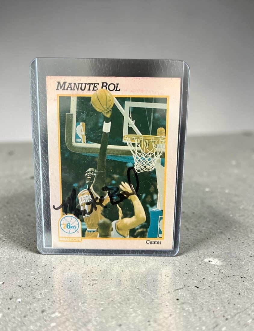 Manute Bol Signed NBA Hoops Collectors Card: This lot is NBA Hoops collectors card, autographed by Manute Bol. If you wish to upgrade to a third party authentication with holographic QR code and item scoring, an additional charge of 30 UK Pound 