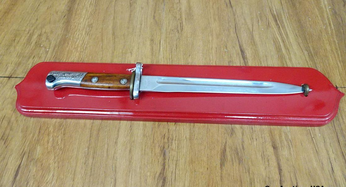 44 Bayonet. Excellent Condition. 9.5" Blade, 15" Overall, Presentation Bayonet From Mitchell's: 44 Bayonet. Excellent Condition. 9.5" Blade, 15" Overall, Presentation Bayonet From Mitchell's Mausers. Wooden Handle. On a Red, Wooden Presentation Plaque. . (61548)