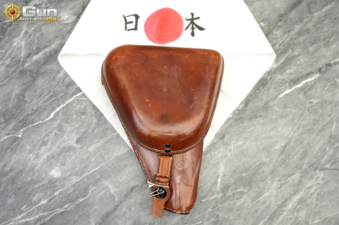 Japanese Type 14 Leather Pistol Holster and Cloth Headband This lot includes a hardshell leather: Japanese Type 14 Leather Pistol Holster and Cloth HeadbandThis lot includes a hardshell leather clamshell holster in very good condition, designed for the Type 14 Nambu pistol, complete with its rear 