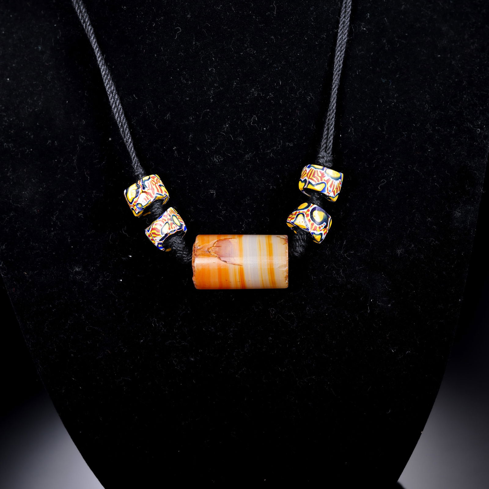 A RARE HIMALAYAN ORANGE AND WHITE BANDED AGATE NECKLACEHIMALAYAN REGION, ANCIENT TO MEDIEVAL PERIOD: DescriptionThis vibrant and structurally balanced necklace is centered around a series of cylindrical banded agate beads (leizi), interspersed with four ancient glass spacer beads (liu-li). The agate