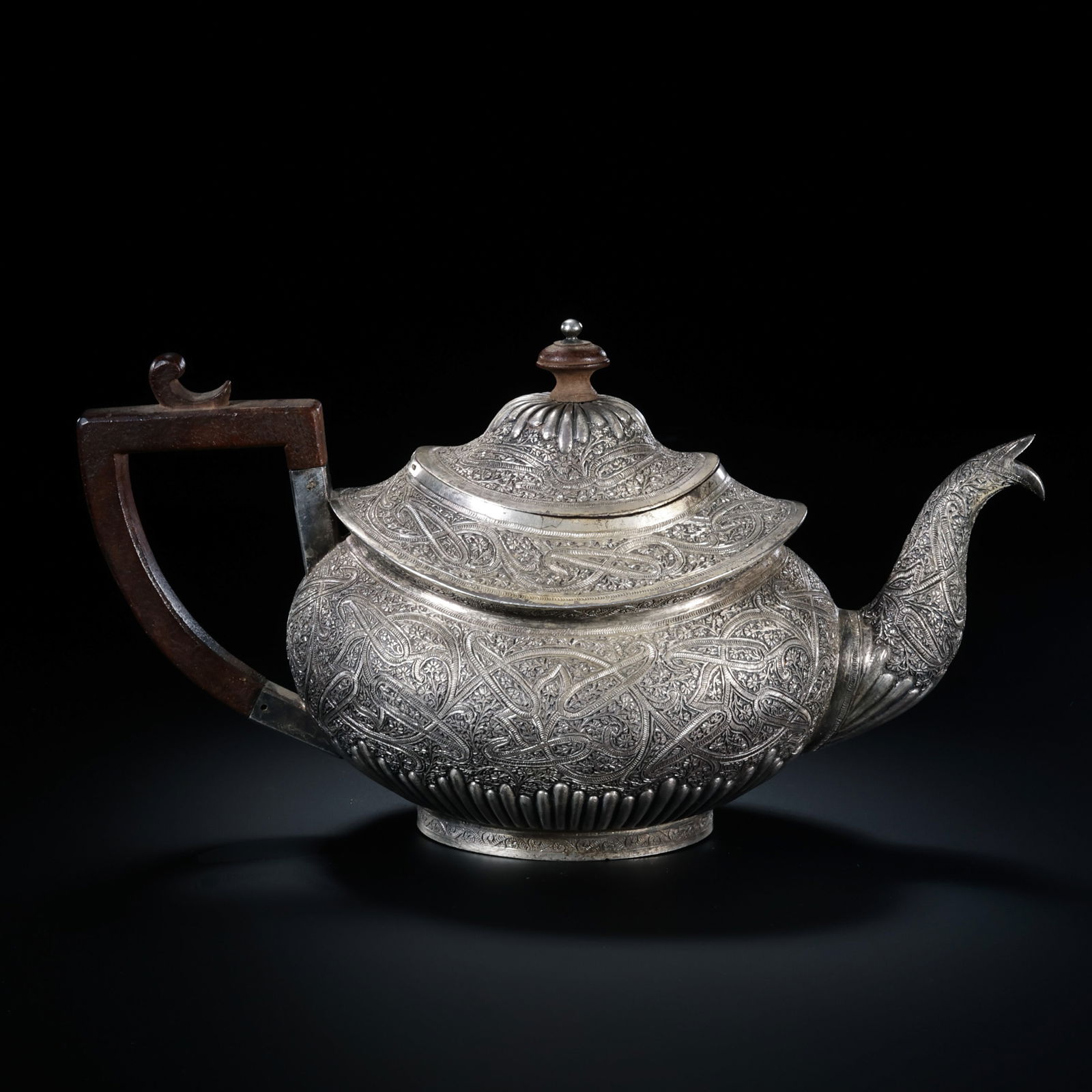 A FINE VICTORIAN STERLING SILVER TEAPOTCIRCA 1860, LONDON / SHEFFIELD: Description This exquisite Victorian sterling silver teapot is a quintessential example of mid-19th-century British silversmithing. Standing on a flared, scrolled foot, the teapot features a compresse