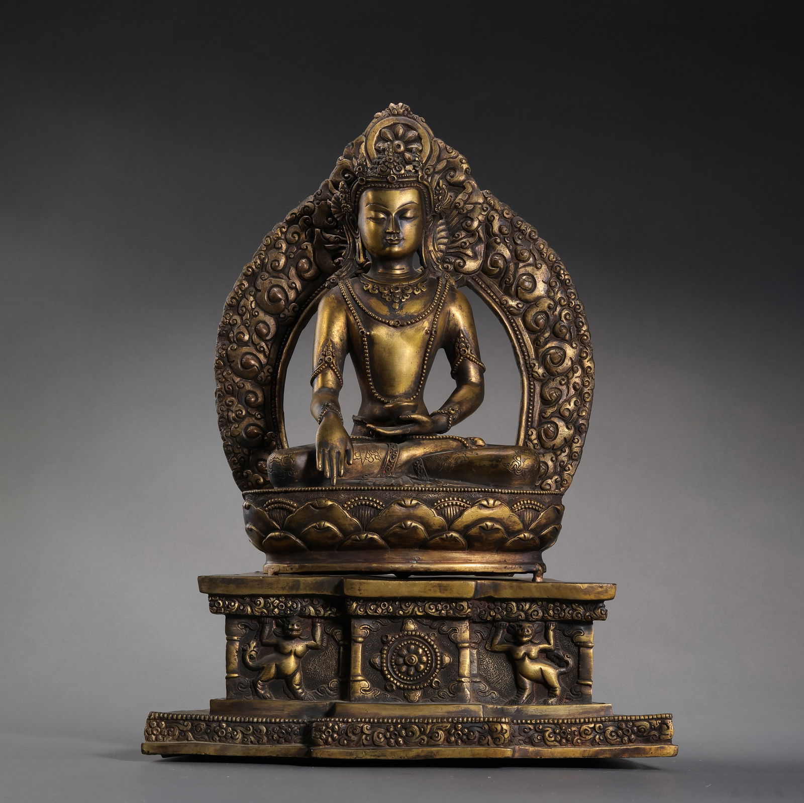 A MAGNIFICENT AND RARE ALLOY COPPER FIGURE OF A SEATED BUDDHA ON A HIGH ALTAR STANDTIBET OR: Description This monumental and masterfully cast alloy copper figure depicts a Buddha—likely Shakyamuni or Akshobhya—seated in the serene posture of dhyanasana (lotus position). The Buddha is elev