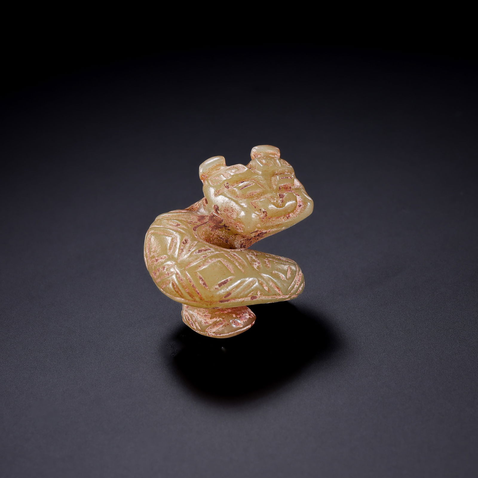A RARE AND IMPORTANT YELLOW JADE 'SPIRAL' DRAGON PENDANTNEOLITHIC PERIOD, PROBABLY HONGSHAN CULTURE: Description This extraordinary ritual ornament is masterfully fashioned from a rare variety of yellow jade (huang-yu), prized for its waxy, honey-toned translucency. The stone exhibits a smooth, unctu