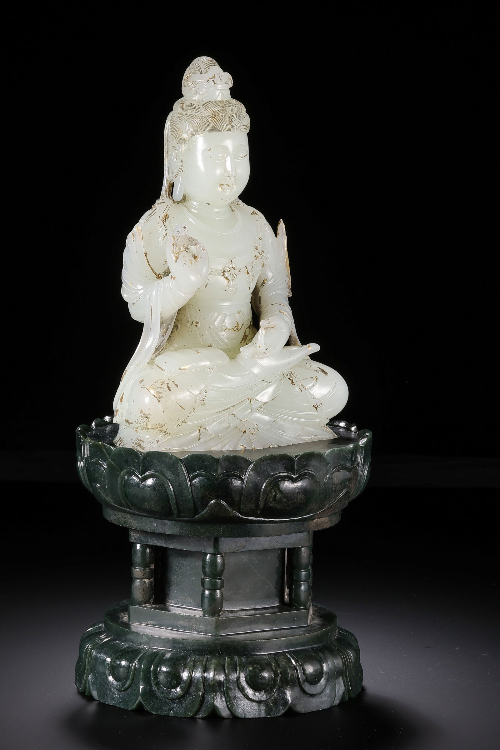 A MONUMENTAL AND RARE JADE FIGURE OF SEATED GUANYIN ON A SPINACH-GREEN JADE LOTUS BASEMING DYNASTY: Description This magnificent two-part Buddhist sculptural group is a testament to the sublime artistry of the Ming dynasty lapidary. The primary figure is masterfully carved from a substantial block o