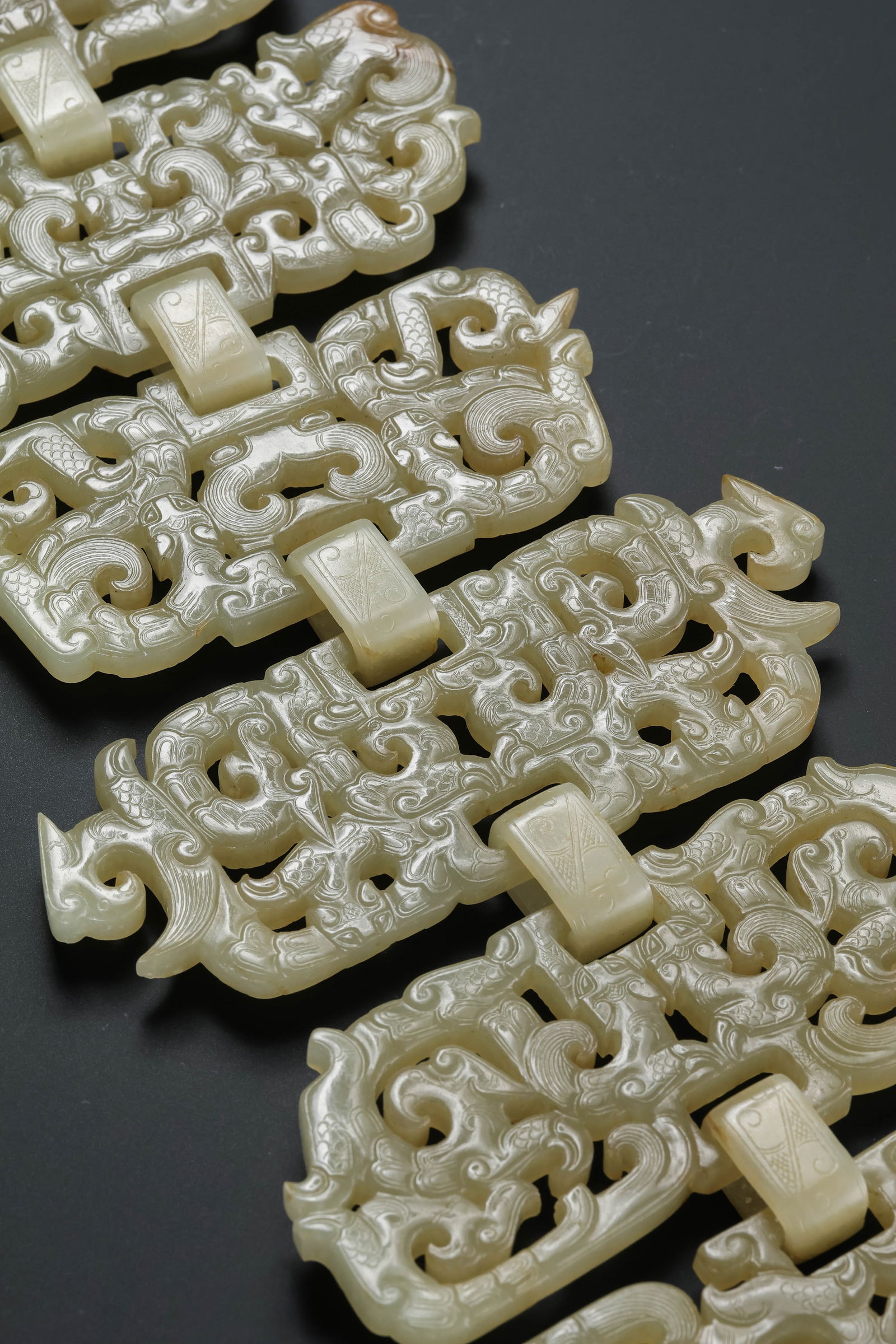 AN EXTRAORDINARY AND RARE TEN-SECTION LINKED WHITE JADE PENDANTWARRING STATES PERIOD TO EARLY HAN: Description This breathtaking tour-de-force of archaic lapidary art is carved from a single, superior block of Hetian white jade. The pendant is composed of ten distinct sections, each interconnected