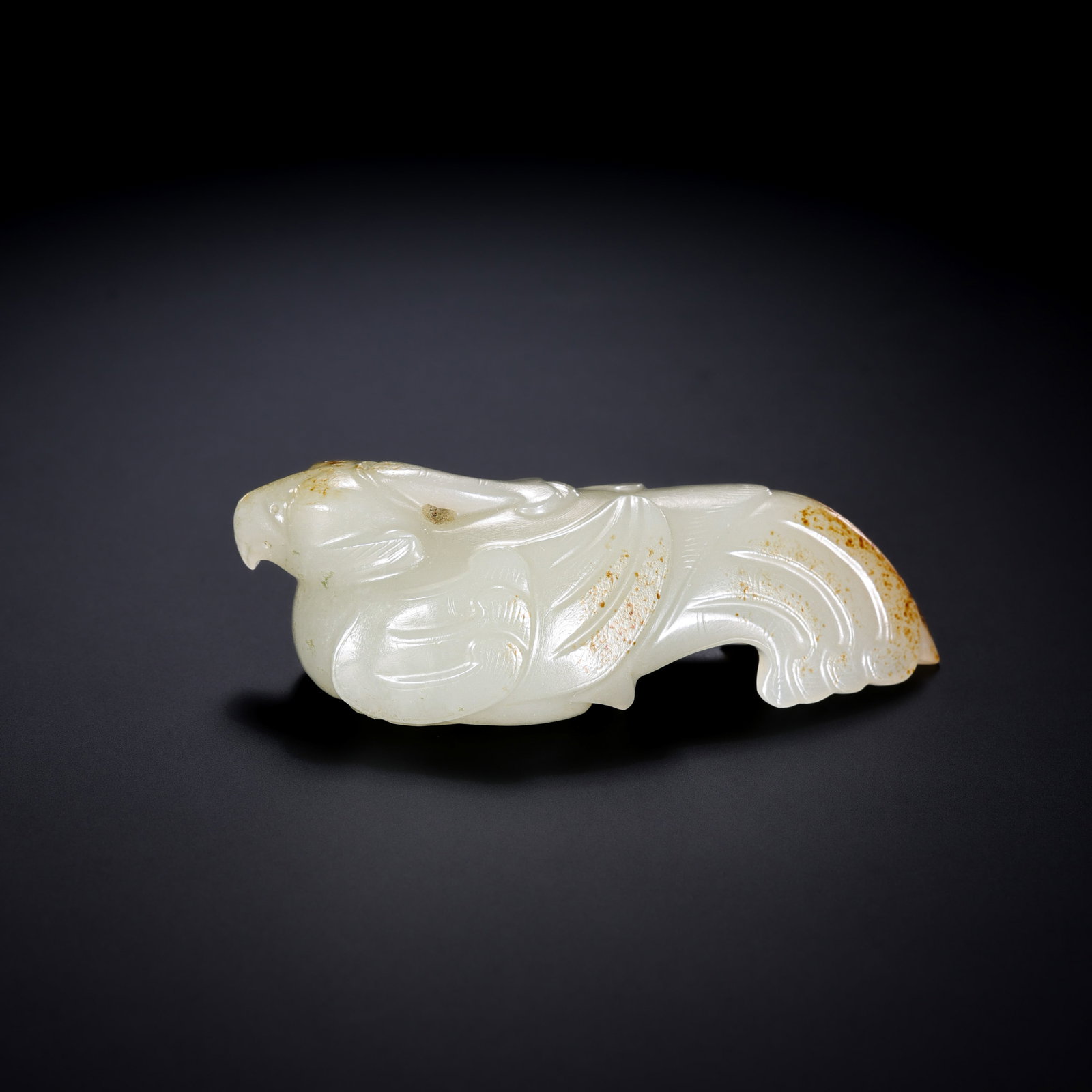 A RARE WHITE JADE FIGURE OF A RESTING PHOENIXWARRING STATES PERIOD (C. 475–221 BC): Description This exquisite jade pendant is masterfully carved from a solid block of Hetian white jade, exhibiting a fine, unctuous luster and a warm, creamy translucency. The stone is remarkably well-