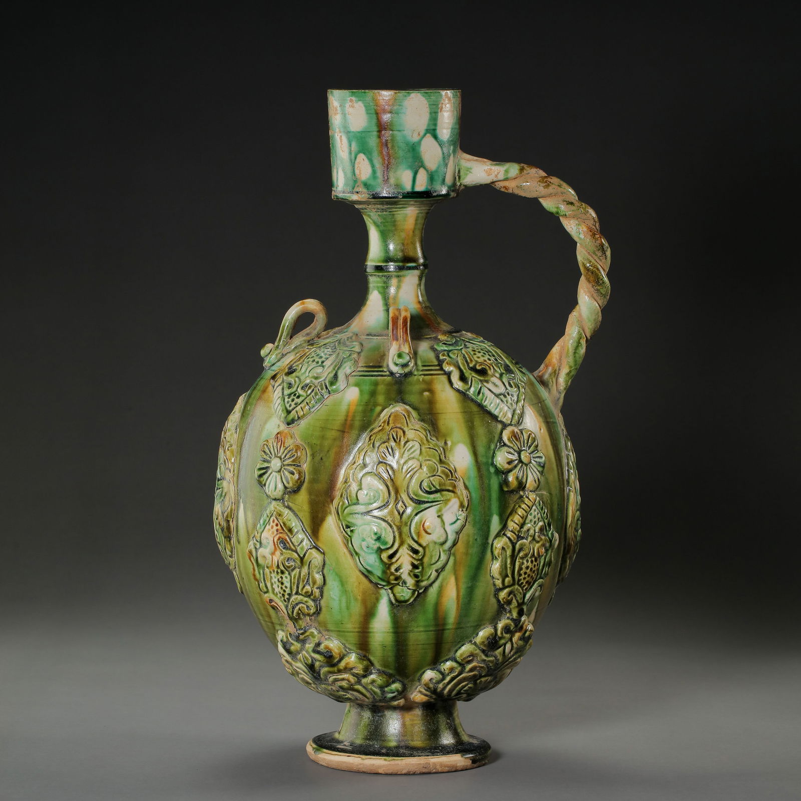 A RARE AND MAGNIFICENT 'SANCAI' PHOENIX-HEADED EWERTANG DYNASTY (618-907): The ewer is elegantly potted with an ovoid body rising from a flared pedestal foot to a slender neck, surmounted by a masterfully sculpted phoenix head as the spout. The phoenix is depicted with a sha