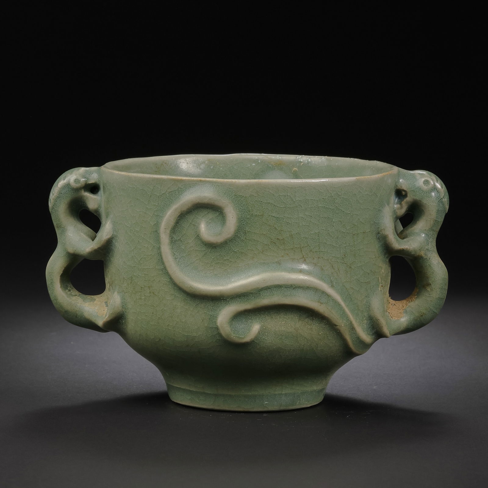 A RARE CELADON-GLAZED 'CHILONG' DOUBLE-HANDLED CUPDONGGOU WARE, YUAN TO EARLY MING DYNASTY: Description This elegantly proportioned cup is a fine example of Donggou ware, exhibiting the refined transition from the robust forms of the Yuan dynasty to the more delicate aesthetics of the early