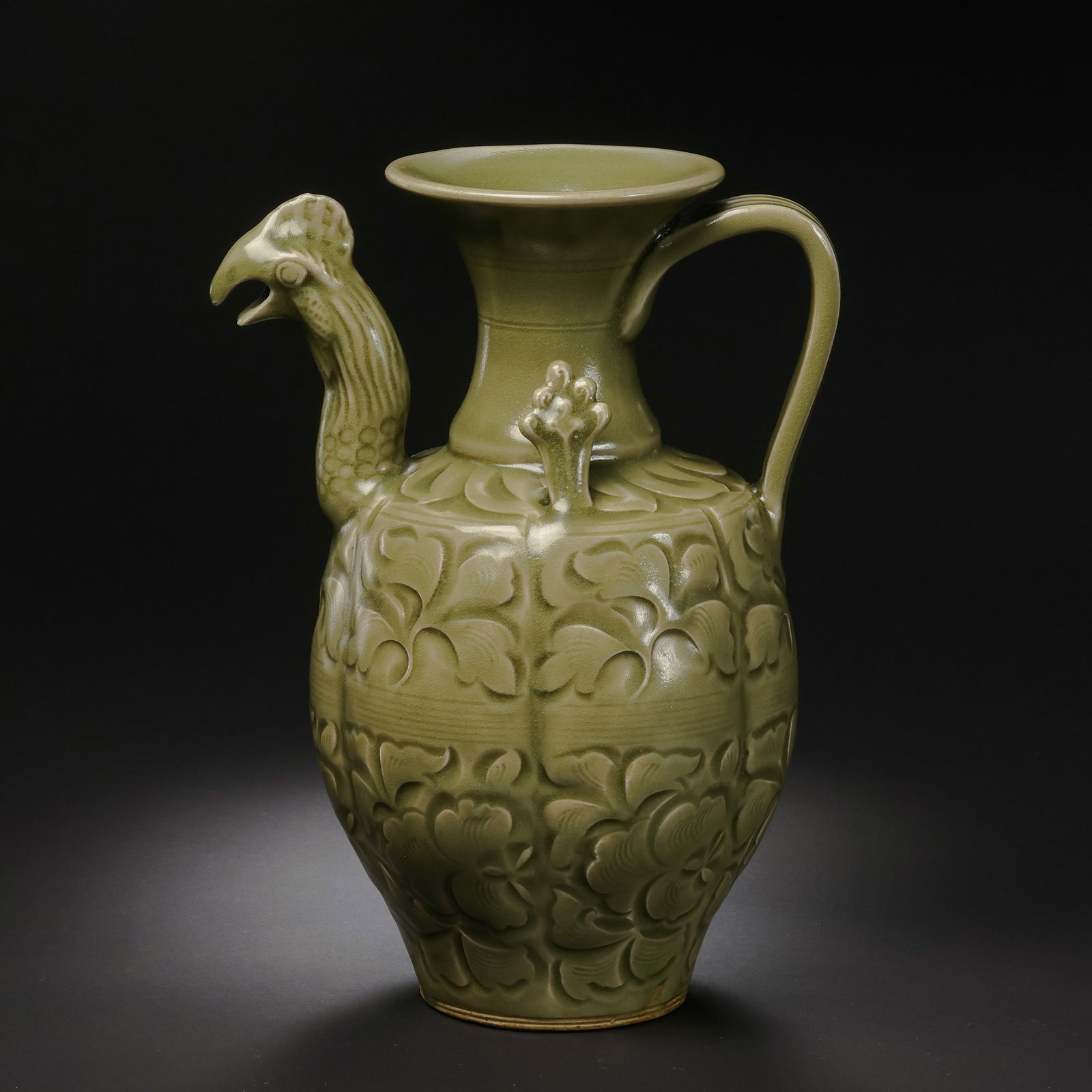 A RARE CELADON-GLAZED 'PHOENIX-HEAD' EWERYAOZHOU WARE, FIVE DYNASTIES PERIOD (10TH CENTURY): Description This magnificent ewer is an exceptional testament to the transition of Yaozhou kilns during the Five Dynasties period. It features a tall, slender neck surmounted by a meticulously sculpte