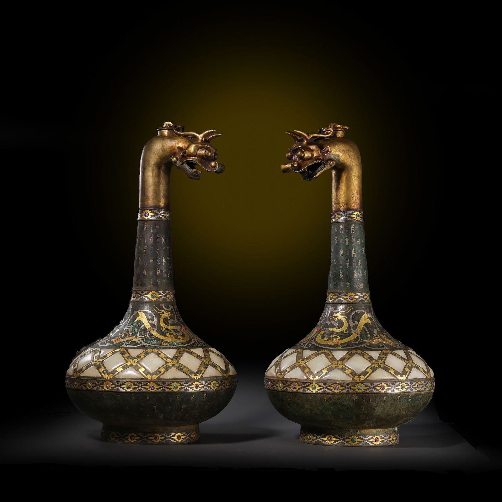 A MAGNIFICENT AND MONUMENTAL PAIR OF INLAID GOLD AND SILVER AND JADE-INLAID 'MYTHICAL BEASTS': Description This exceptional pair of 'Hu' vases represents the pinnacle of multi-media craftsmanship during the Warring States period. Each vessel is designed with a slender long neck (chang-jing) ris