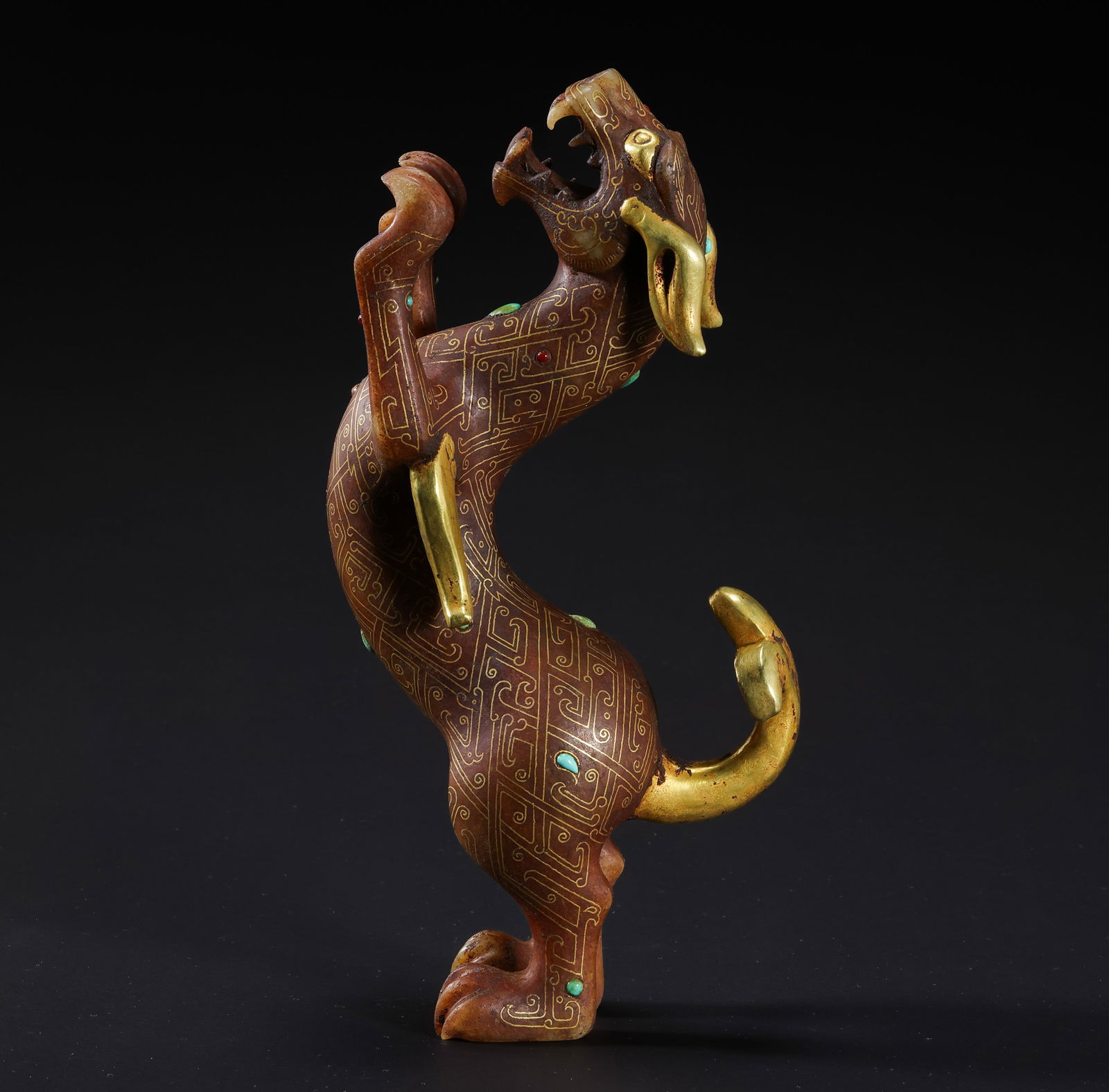 A SPECTACULAR GOLD-INLAID AND GEM-SET HETIAN JADE BIPEDAL MYTHICAL BEASTWARRING STATES PERIOD: Description This extraordinary sculpture is masterfully carved from a substantial, high-density block of Hetian white-celadon jade. The creature is depicted in a powerful, bipedal standing posture , i