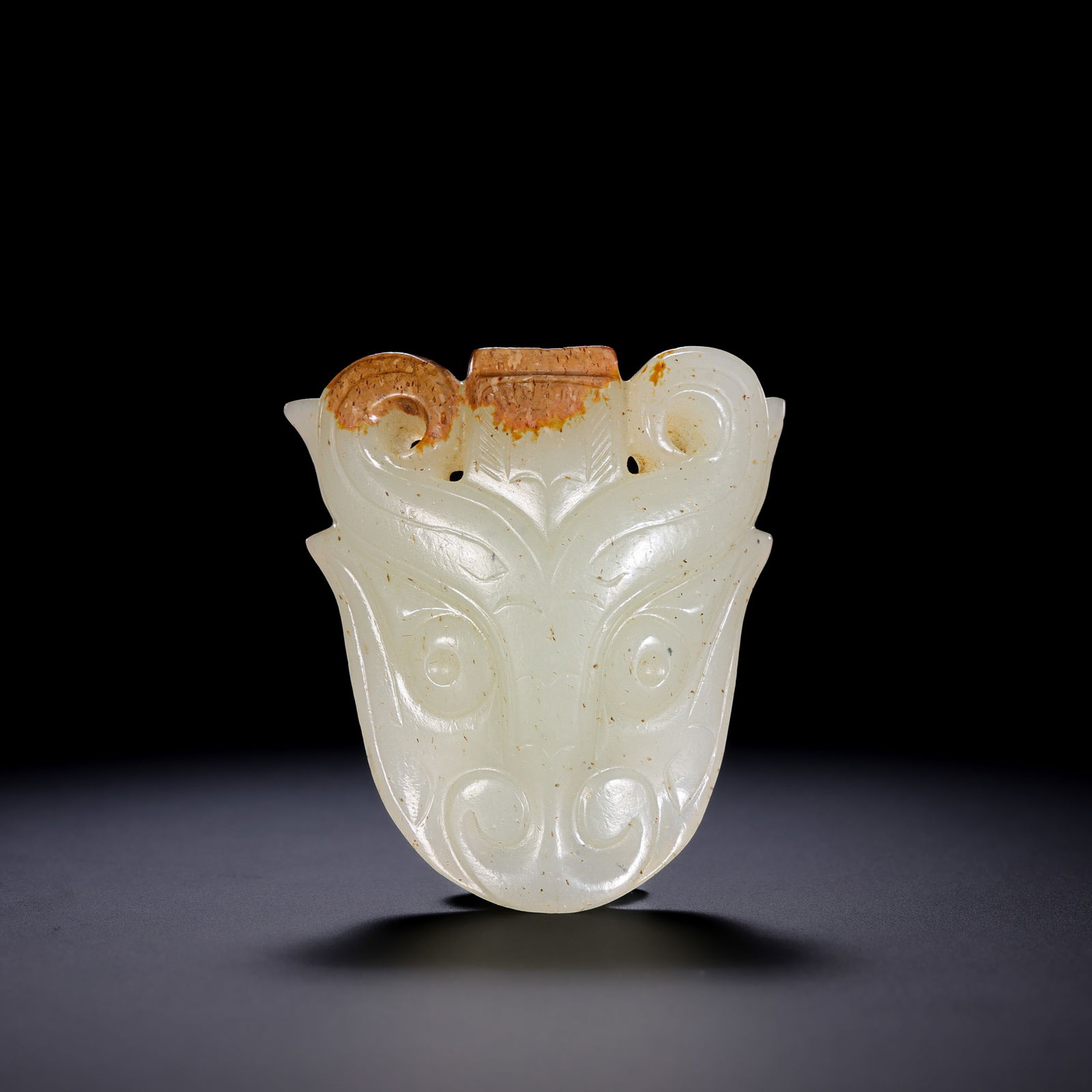 A RARE AND FINELY CARVED WHITE JADE 'ANIMAL MASK' PENDANT (LEIZI)WESTERN ZHOU DYNASTY (C. 1046–771: Description This exceptional jade ornament is masterfully carved from a substantial block of high-quality Hetian white jade, exhibiting a remarkably warm and unctuous luster. The stone is characterize