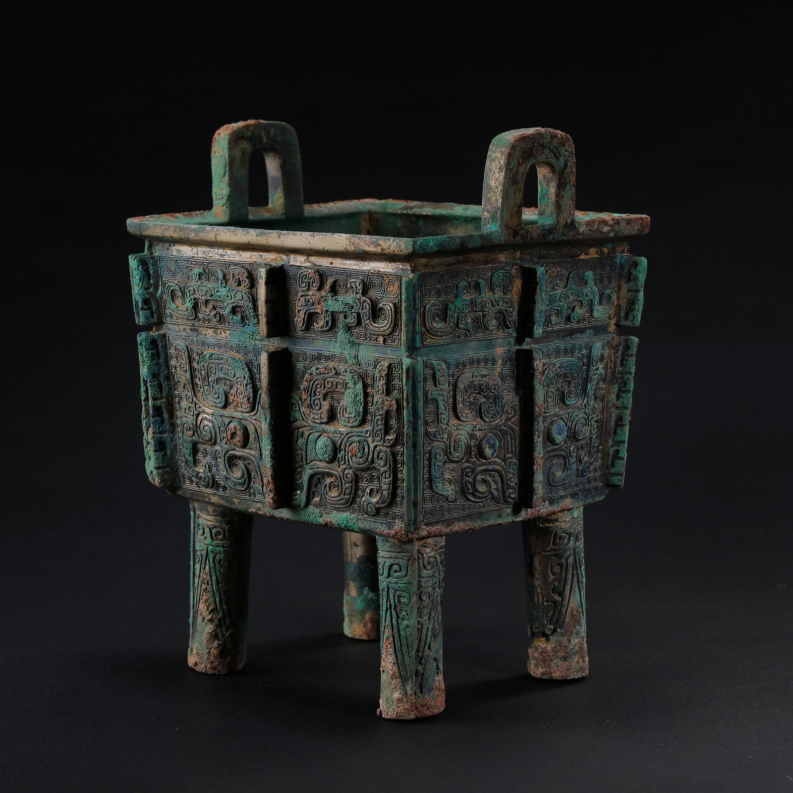 AN IMPORTANT AND FINELY CAST BRONZE RITUAL FOOD VESSEL,DINGEARLY WESTERN ZHOU DYNASTY, 11TH – 10TH: DescriptionThe vessel is powerfully cast with a deep tri-lobed body supported on three cylindrical legs. The exterior is crisply decorated around the neck with a vibrant band of taotie masks, each cen
