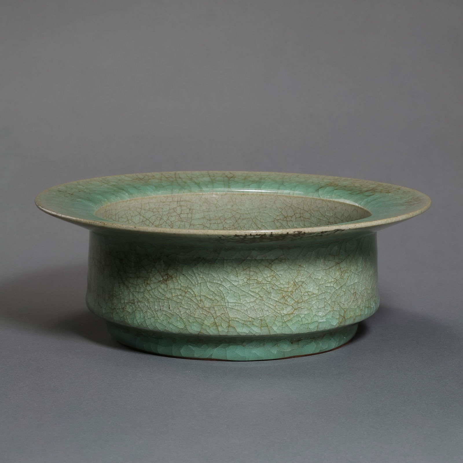 A RARE AND ELEGANT LONGQUAN CELADON FLARED WASHERSONG DYNASTY (960–1279): DescriptionThis exquisitely potted washer features a wide, flared rim (pie-kou) that gracefully curves outward, rising from a short, tapered foot to a shallow, expansive body. The silhouette is one of