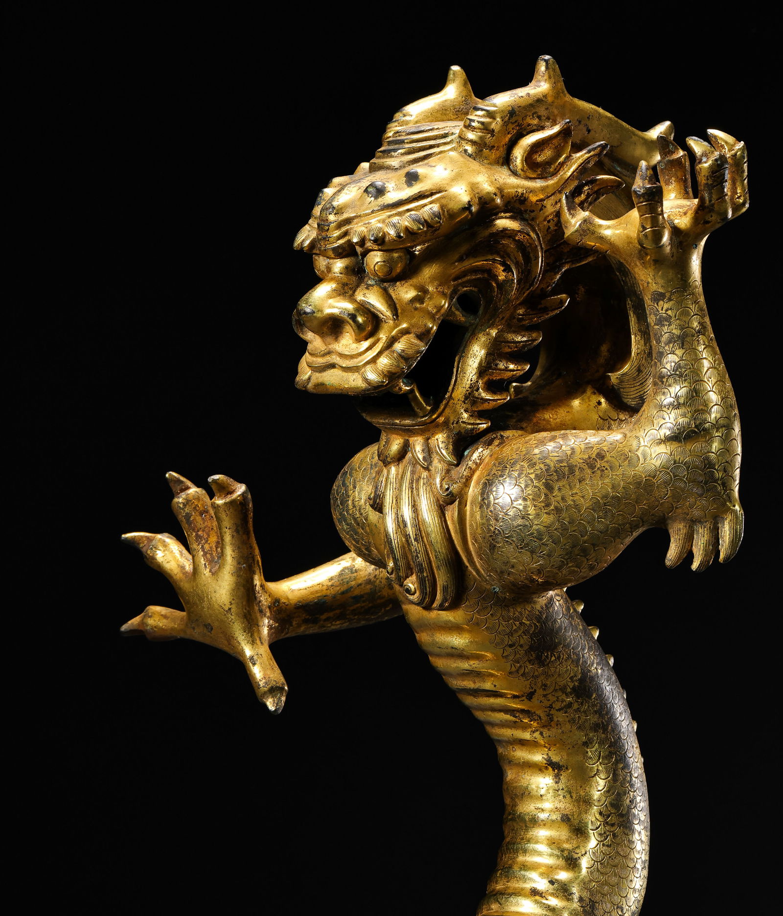AN EXTREMELY RARE AND MAGNIFICENT GILT-BRONZE FIGURE OF A STANDING DRAGONMING DYNASTY, YONGLE PERIOD: DescriptionThe powerfully cast figure is shown standing four-square with its sinuous, undulating body terminating in a powerful tail. The head is vibrantly modeled with wide-open eyes under bushy brow