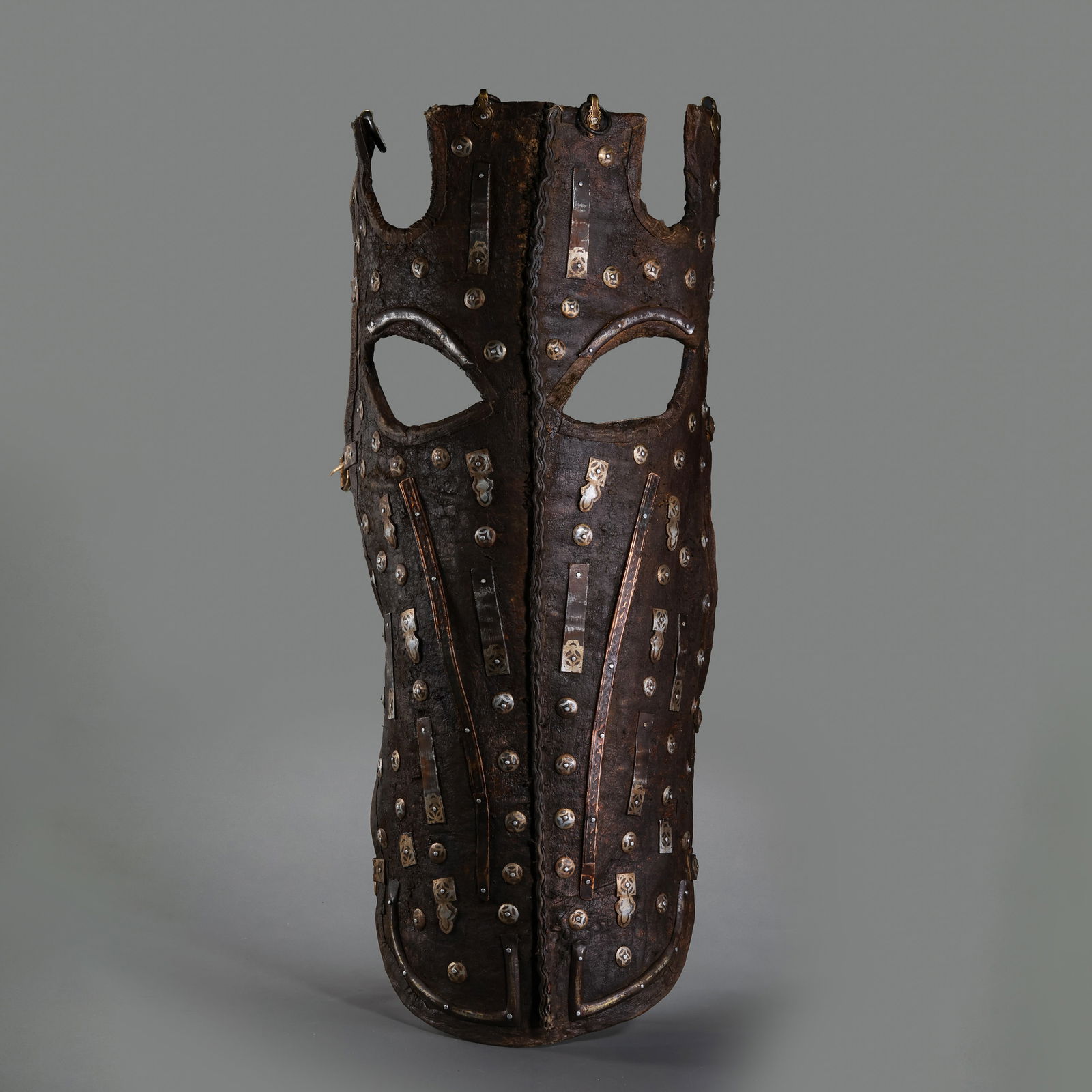 A RARE AND MAGNIFICENT LEATHER HORSE CHAMFRON WITH SILVER-INLAID FITTINGSMING DYNASTY OR LATER (14TH: Description This extraordinary piece of equestrian armor, or chamfron, is expertly crafted from thick, durable lacquered leather (piga), designed to protect the horse's head while projecting a formida