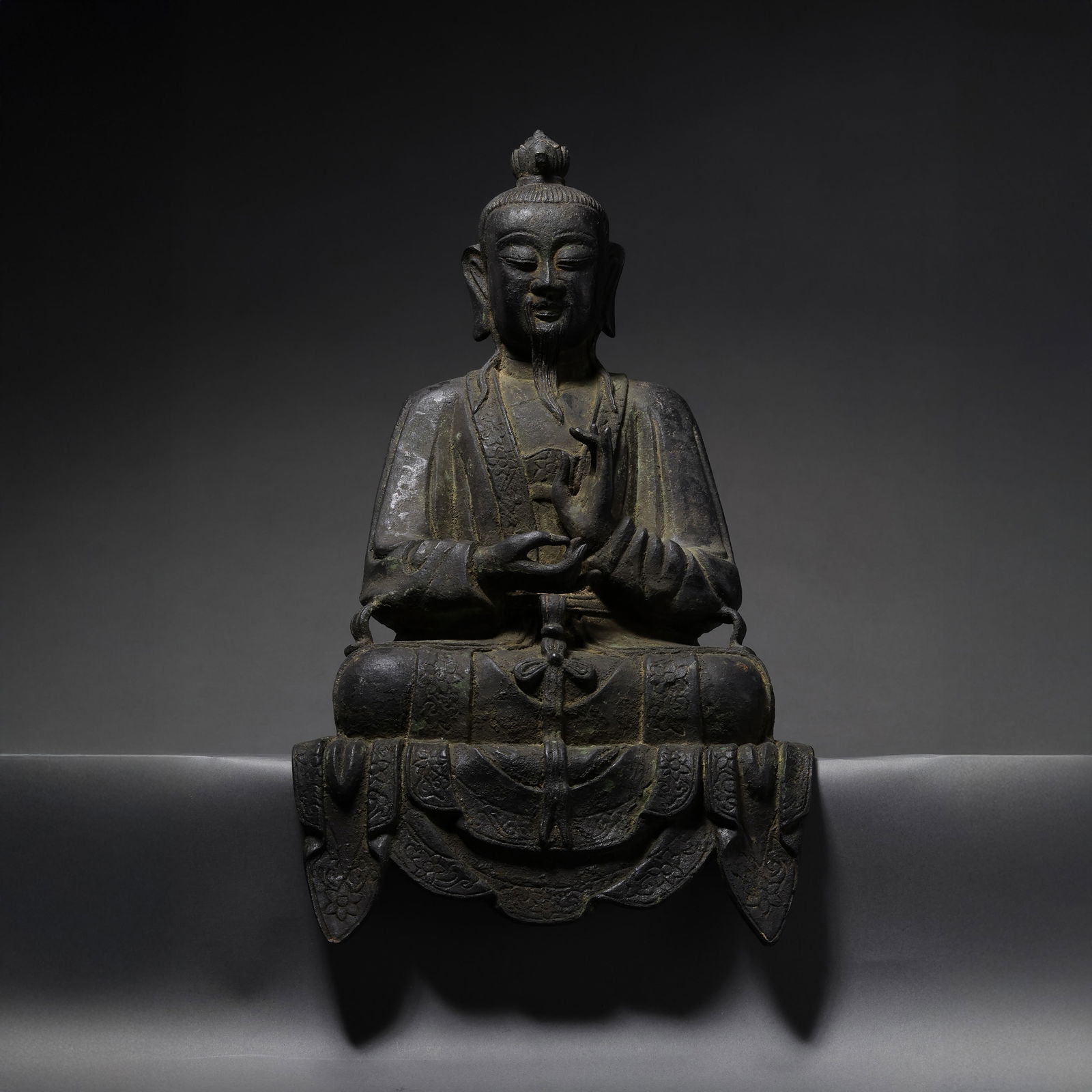 A RARE AND SPIRITED BRONZE FIGURE OF A SEATED TAOIST CELESTIAL MASTER OR IMMORTALMING DYNASTY: Description This exceptional bronze figure depicts a senior Taoist deity, likely a Celestial Master (Tianshi) or a revered Patriarch (Zushi), seated in a dignified posture. The immortal is portrayed w