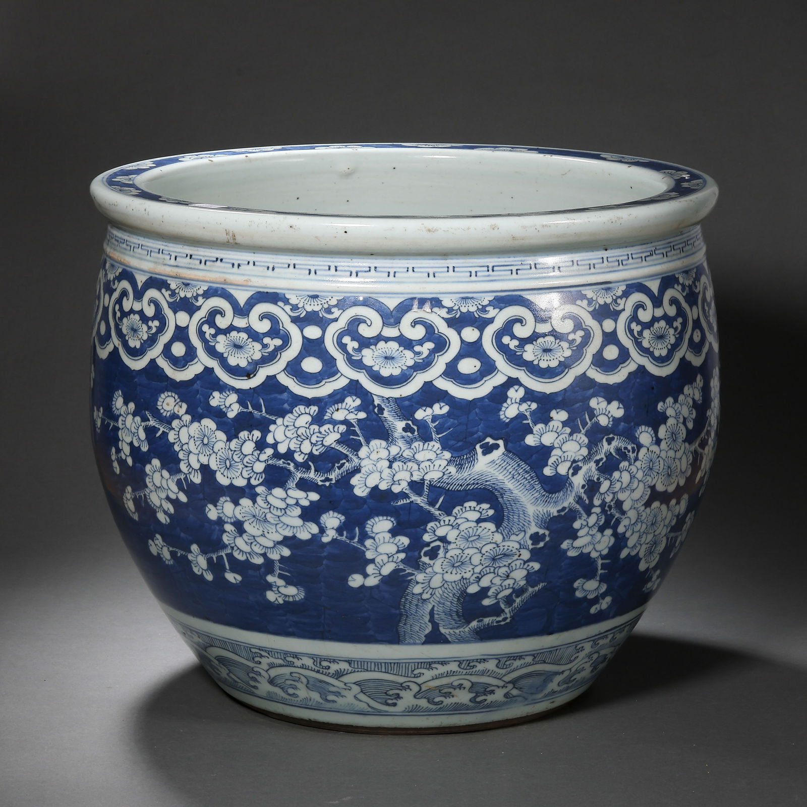 A LARGE BLUE AND WHITE 'PRUNUS' FISH BOWLQING DYNASTY, 18TH/19TH CENTURY: Description The fish bowl is robustly potted with deep, rounded sides tapering towards a flat base and terminating in a broad, thickened rim. The exterior is masterfully painted in vibrant tones of un