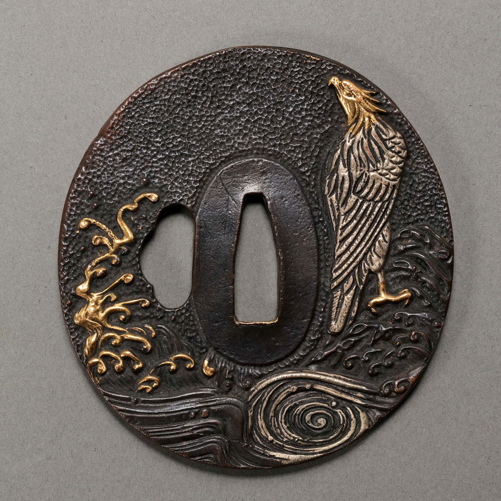 A FINE GILT-BRONZE HIGH-RELIEF 'EAGLE AND RISING SUN' TSUBAEDO PERIOD (17TH–19TH CENTURY): Description This exceptional Tsuba (Sword Guard) is a masterwork of late Edo period metalwork, possibly associated with the Mito or Higo schools of craftsmen. The guard is of classic circular form (ma