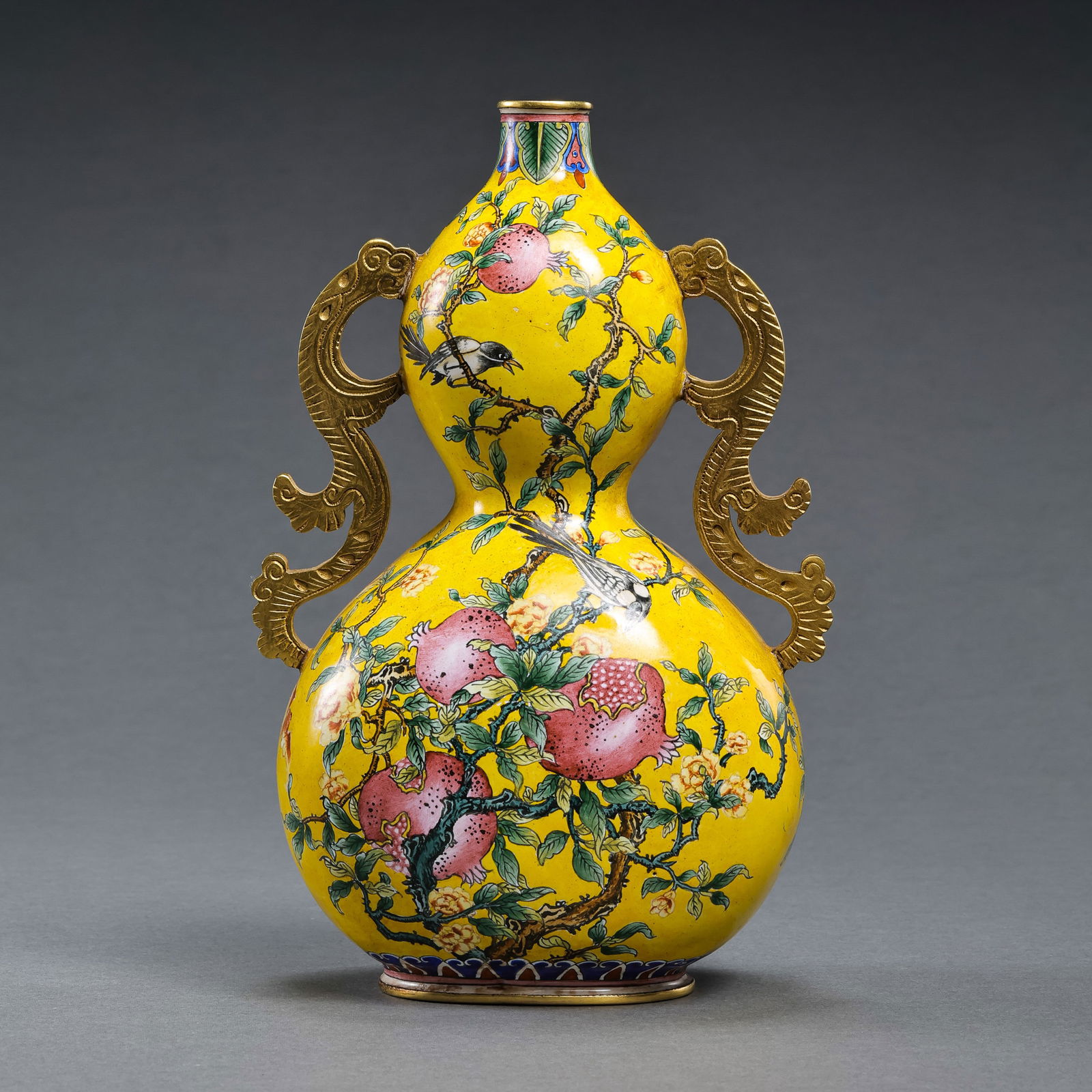 A RARE AND EXQUISITE IMPERIAL GILT-COPPER AND ENAMEL 'POMEGRANATE' DOUBLE-GOURD VASEMARK AND PERIOD: DescriptionThe vessel is elegantly potted in the form of a double-gourd (hulu), with the lower globular bulb rising to a smaller upper bulb, flanked by a pair of delicate Ruyi-shaped handles that brid
