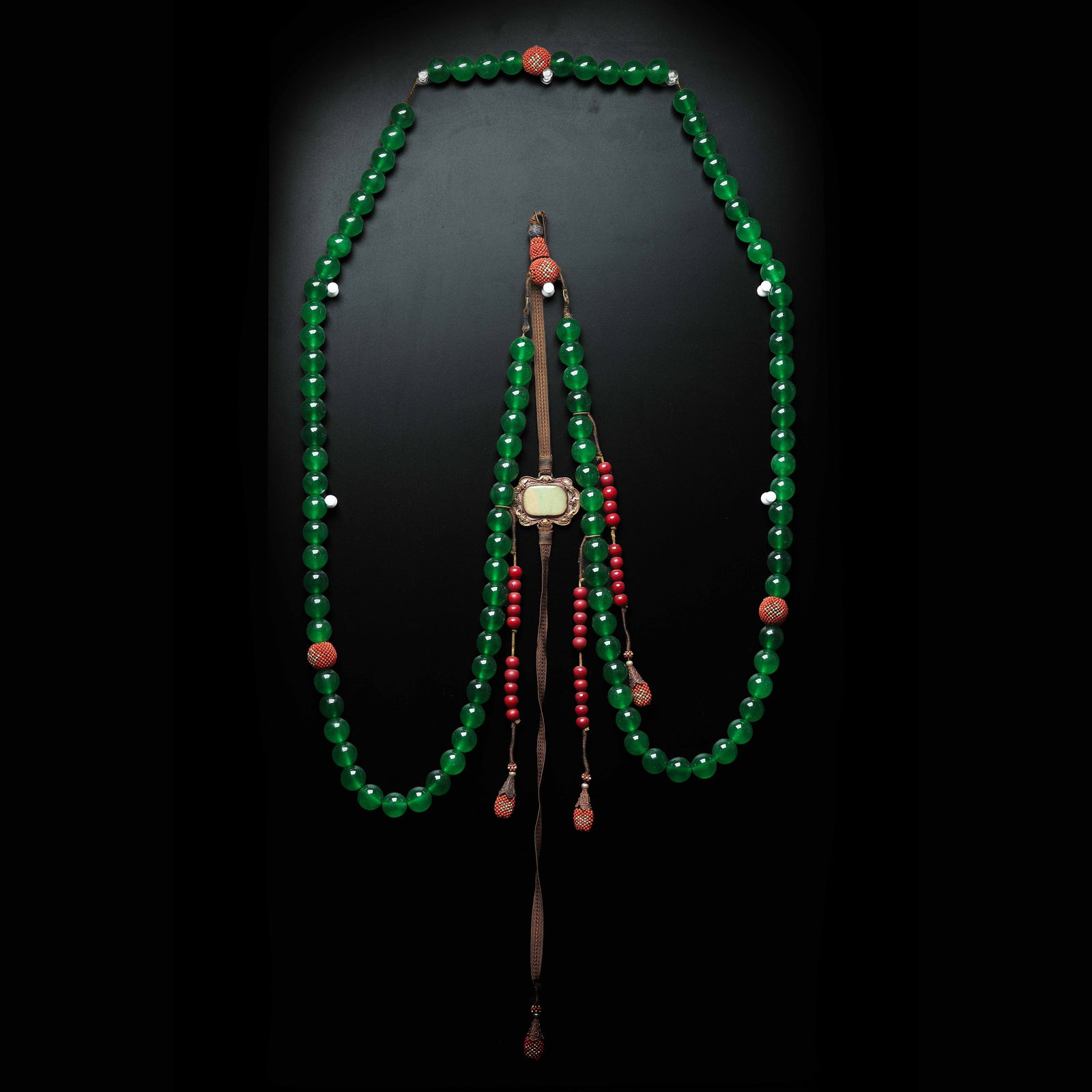 A RARE AND IMPORTANT JADEITE AND RED CORAL COURT NECKLACE (CHAOZHU)QING DYNASTY (1644–1911): Description This magnificent Chaozhu (Court Necklace) is a quintessential symbol of the rigid social hierarchy and refined luxury of the Qing Imperial Court. The necklace is impeccably strung with 108