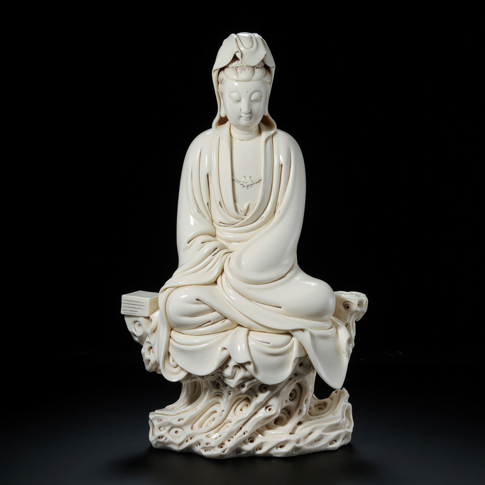 A MONUMENTAL DEHUA WHITE-GLAZED FIGURE OF SEATED 'CROSSING THE SEA' GUANYINQING DYNASTY, 17TH - 18TH: Description This colossal and masterfully sculpted Blanc-de-Chine figure depicts Guanyin, the Bodhisattva of Compassion, in a majestic seated posture atop a dramatic pedestal of swirling sea waves (ha
