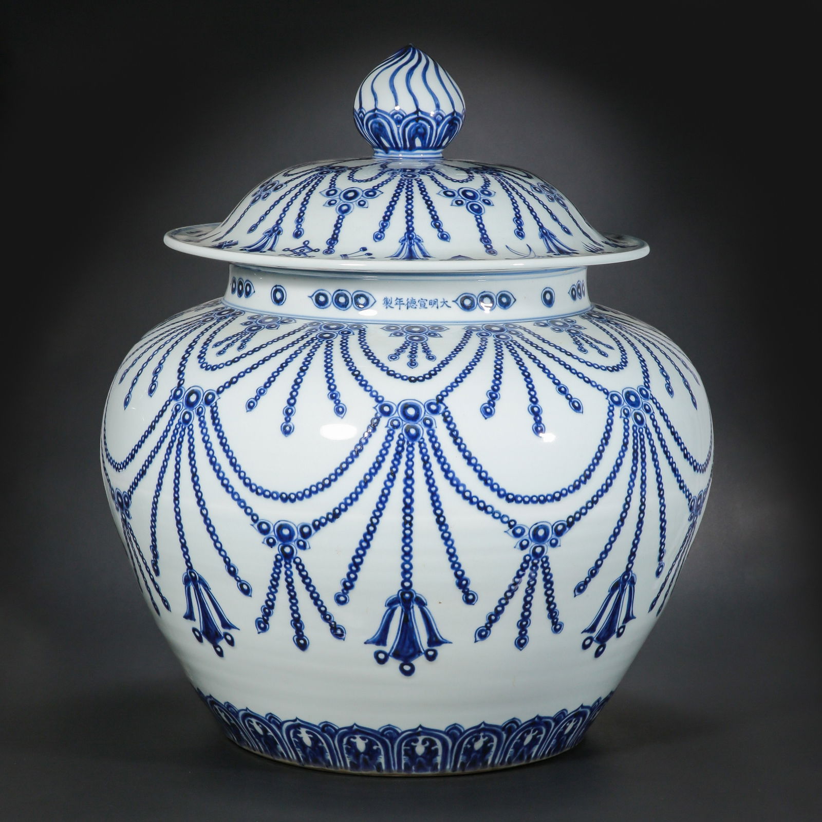 A MONUMENTAL AND RARE BLUE AND WHITE 'BEADED TASSEL' JAR AND COVERXUANDE SIX-CHARACTER MARK IN A: Description The jar is of monumental proportions and sturdily potted, featuring an elegantly rounded body and a broad, waisted neck. It is surmounted by its original domed cover with a bud-shaped fini