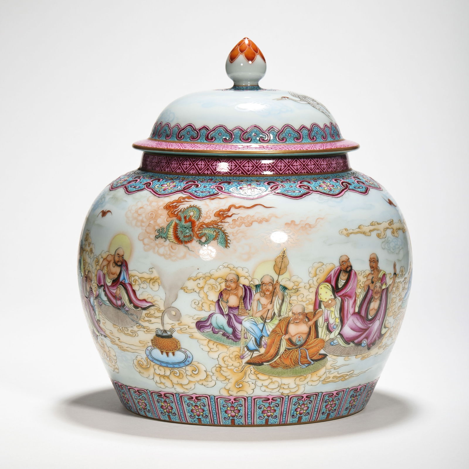 FINE AND MAGNIFICENT FAMILLE-ROSE 'LUOHAN' COVERED JAR QIANLONG FOUR-CHARACTER MARK IN UNDERGLAZE: The jar is elegantly potted with a robust, globular body tapering to a recessed base, vibrantly enameled around the exterior with a continuous procession of the Eighteen Luohans. The figures are rende