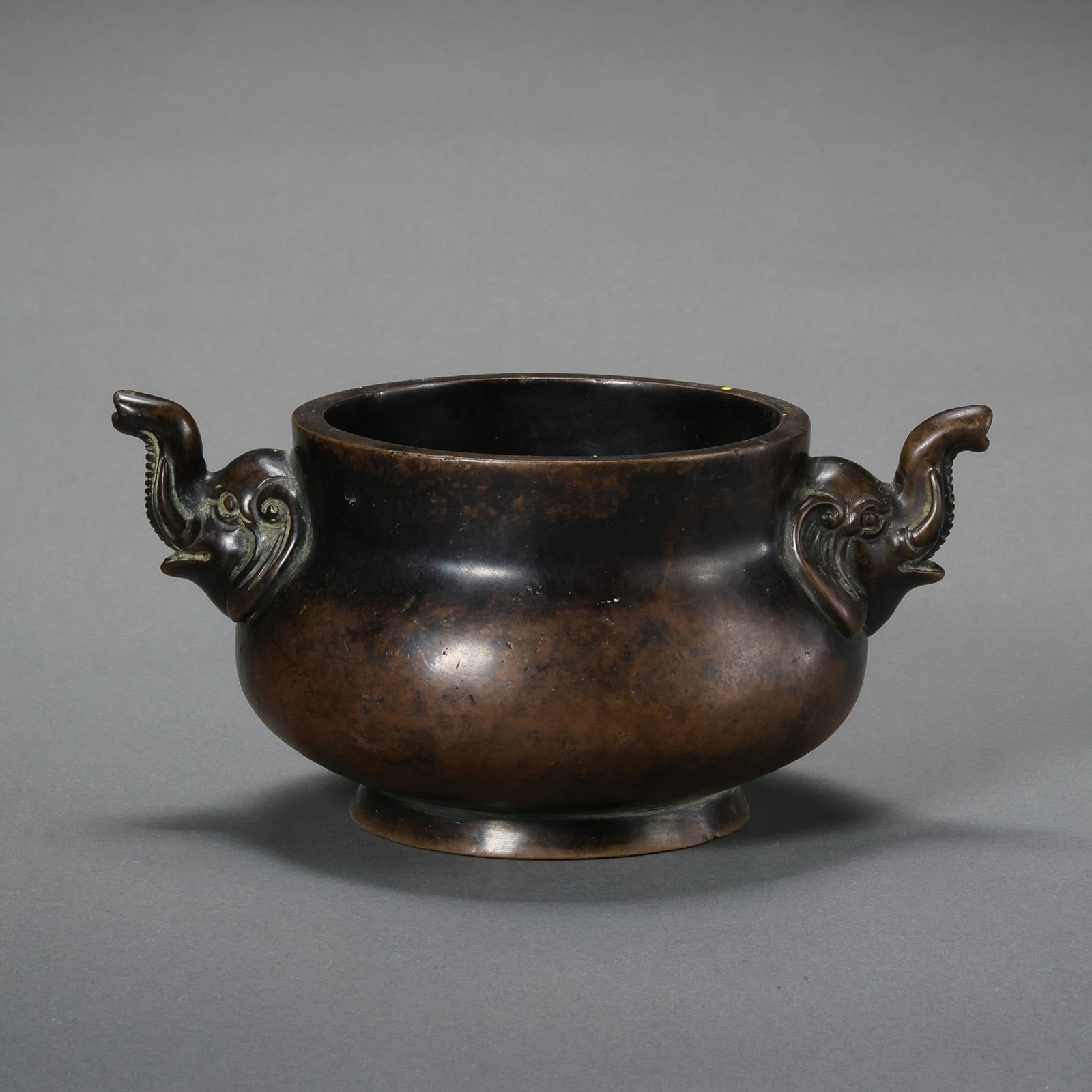 A FINELY CAST BRONZE 'ELEPHANT-HEAD' HANDLED CENSERMARK OF XUANDE, MING DYNASTY (1368–1644): Description This elegantly proportioned bronze censer features a compressed globular body of Gue-form, rising from a stable ring foot (quan-zu). The vessel is flanked by a pair of meticulously sculpte