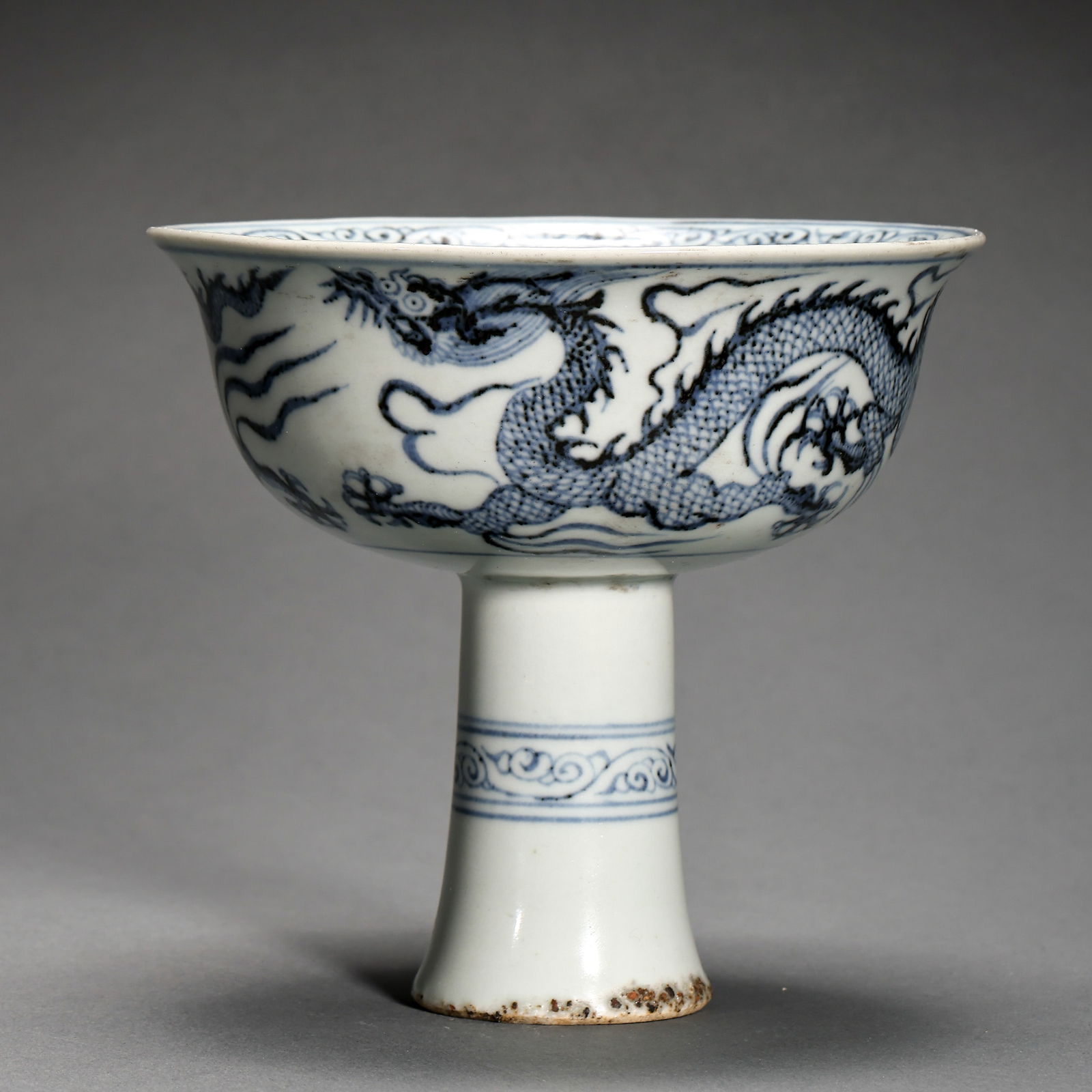 A RARE BLUE AND WHITE 'DRAGON' STEM CUPEARLY MING DYNASTY (15TH CENTURY): Description This exquisitely proportioned Stem Cup (gao-zu-bei) is a significant testament to the refined ceramic artistry of the early 15th century. The vessel features a wide, flared bowl with thin