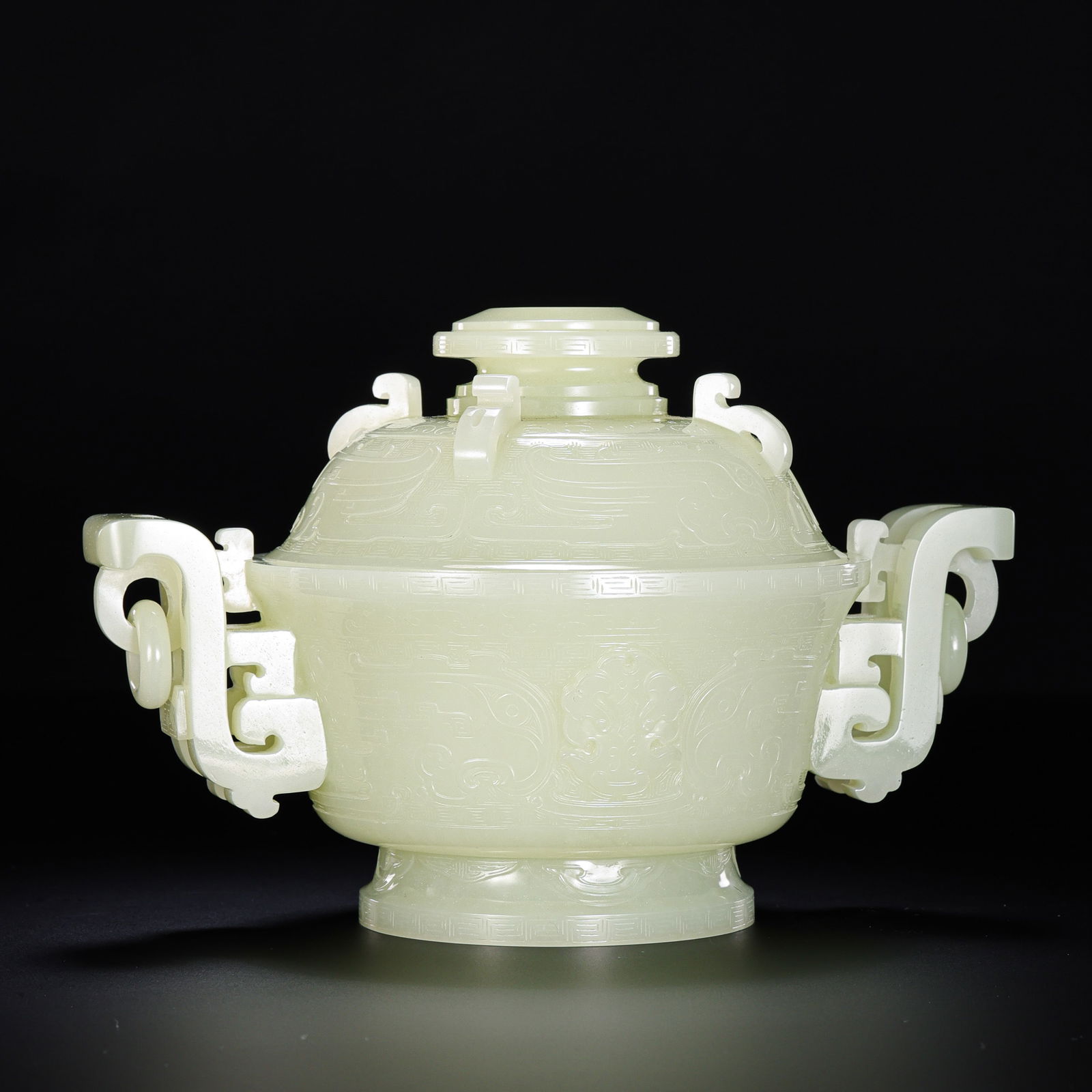 A MAGNIFICENT AND RARE WHITE JADE ARCHAISTIC CENSER AND COVERQIANLONG PERIOD (1736–1795): Description This monumental censer is masterfully carved from a single, substantial block of Hetian white jade of exceptional purity and even, translucent tone. The stone possesses the highly coveted