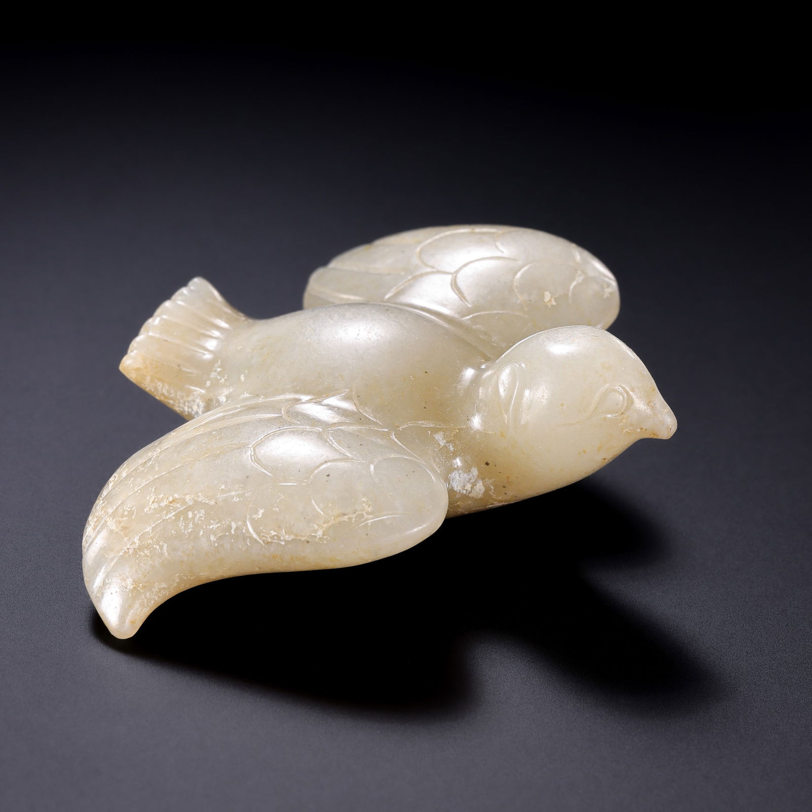 A RARE WHITE JADE FIGURE OF A 'SOARING BIRD'NEOLITHIC PERIOD TO WESTERN ZHOU DYNASTY (C. 2000–1000: Description This exceptional jade carving is fashioned from high-quality Hetian white jade, possessing a warm, unctuous "mutton-fat" luster. The stone exhibits subtle, natural areas of russet skin (za