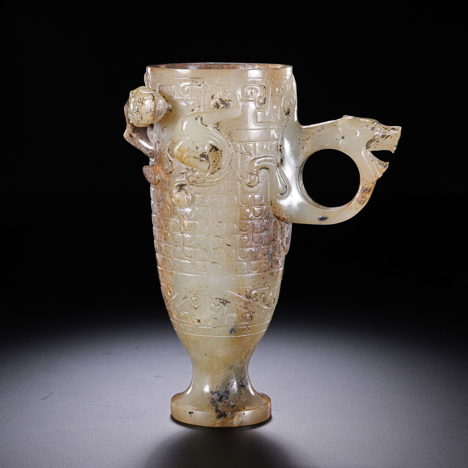 RARE AND MAGNIFICENT WHITE JADE HIGH-RELIEF 'CHILONG' CUP WITH MYTHICAL BEAST HANDLEWARRING STATES: Description This exceptional vessel is masterfully fashioned from a substantial block of translucent Hetian white jade (nephrite). The cup is of elegant, slightly flared cylindrical form, supported by