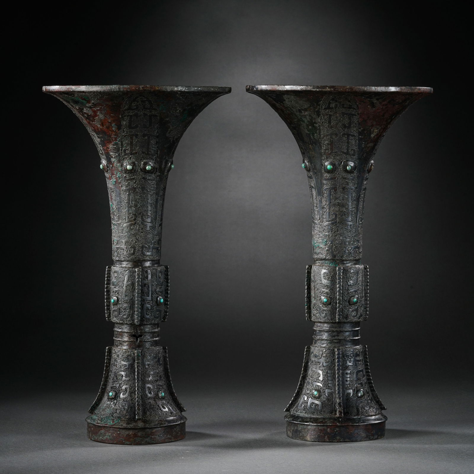 AN EXTREMELY RARE PAIR OF TURQUOISE-INLAID BRONZE VASES,GUWARRING STATES PERIOD (475–221 BC): DescriptionEach vessel is of archaic gu form, elegantly proportioned with a wide flared rim, a central bulging mid-section, and a splayed foot. The body is intricately cast and recessed to receive a l
