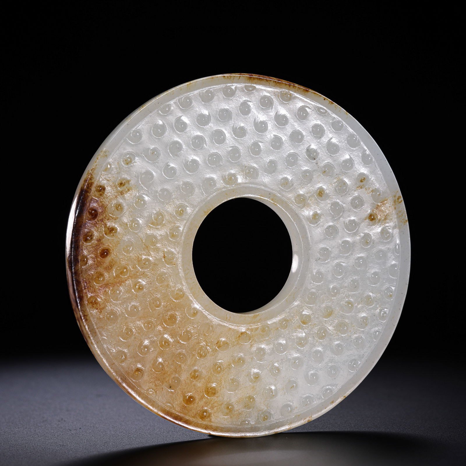 A RARE AND ELEGANT HETIAN WHITE JADE 'TADPOLE-GRAIN' RITUAL DISC,BI, WARRING STATES TO HAN DYNASTY: Description The ritual ornament is masterfully fashioned into a circular disc with a central aperture, expertly carved from a translucent slab of Hetian white jade (nephrite). The piece is sumptuously