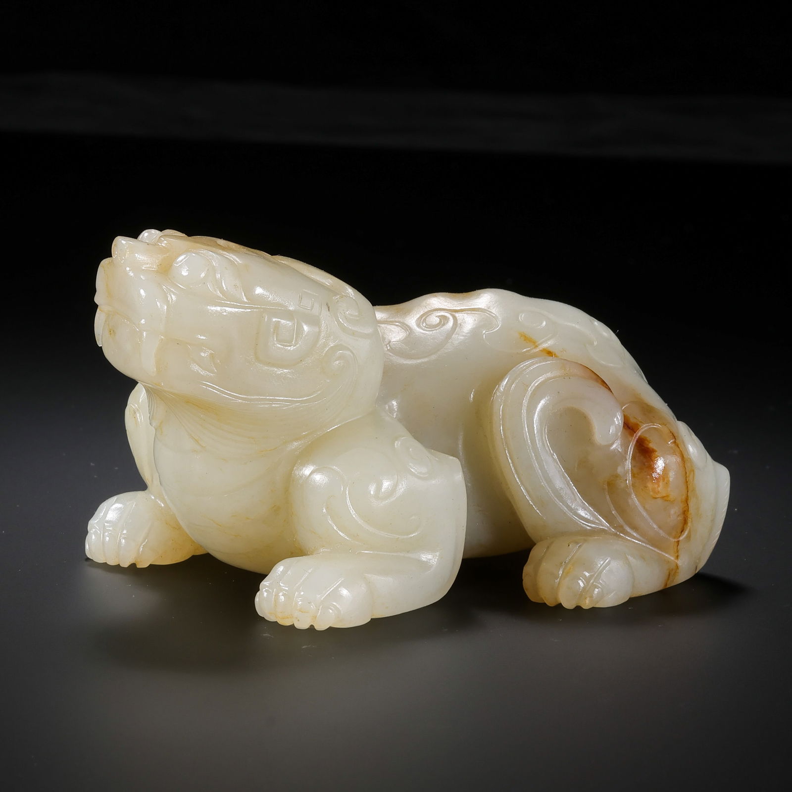 A RARE AND IMPOSING WHITE JADE RECLINING MYTHICAL BEASTMING DYNASTY OR EARLIER (14TH – 17TH: Description This monumental jade sculpture is masterfully carved in the round from an exceptionally dense and substantial block of Hetian white jade. The stone possesses a warm, unctuous "mutton-fat"