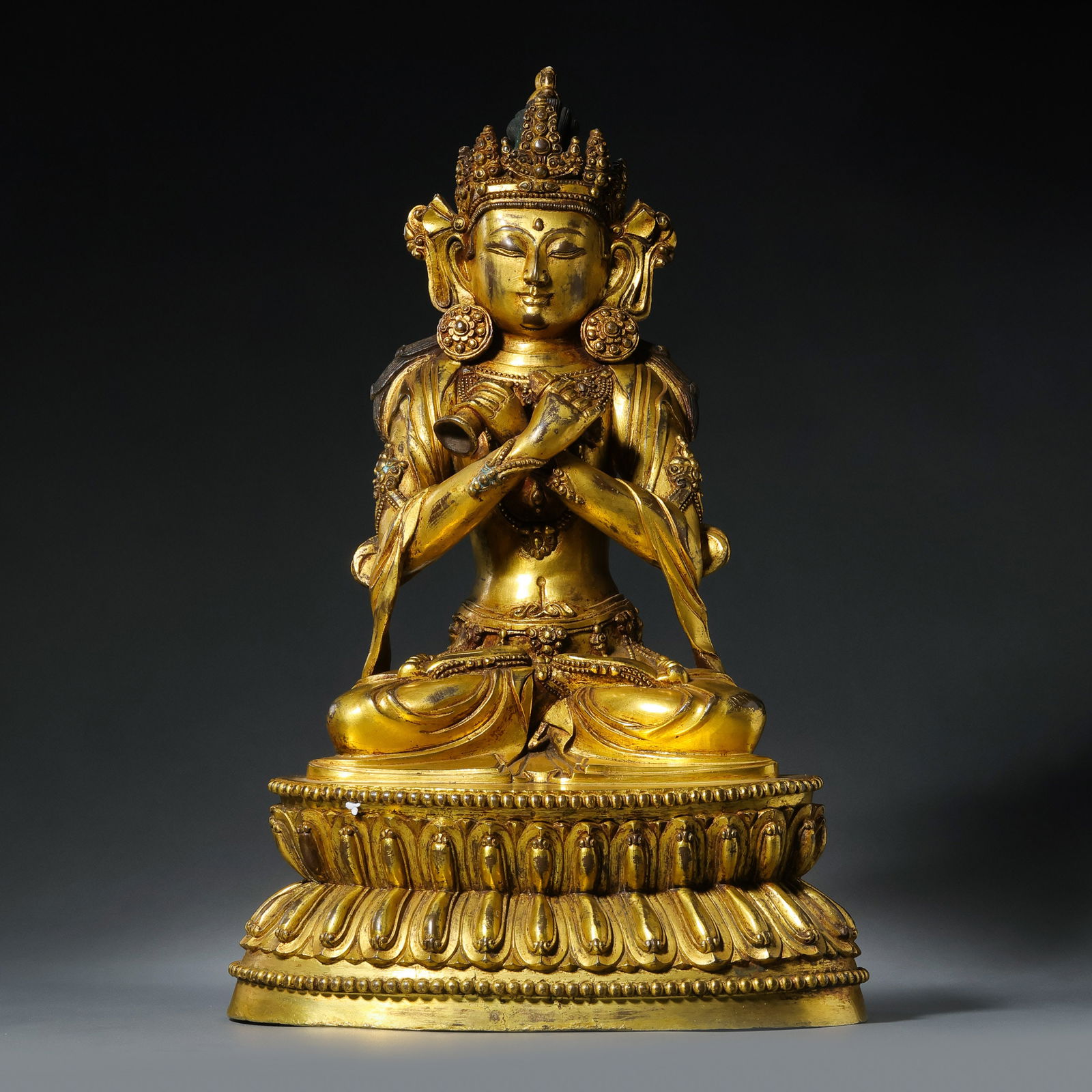 A MAGNIFICENT AND RARE GILT-BRONZE FIGURE OF VAJRASATVATIBET, 15TH - 16TH CENTURY: Description This monumental and exquisitely cast figure depicts Vajrasatva, the 'Vajra Being,' seated in the meditative posture of vajraparyankasana on a double-lotus pedestal. The statue is cast in h