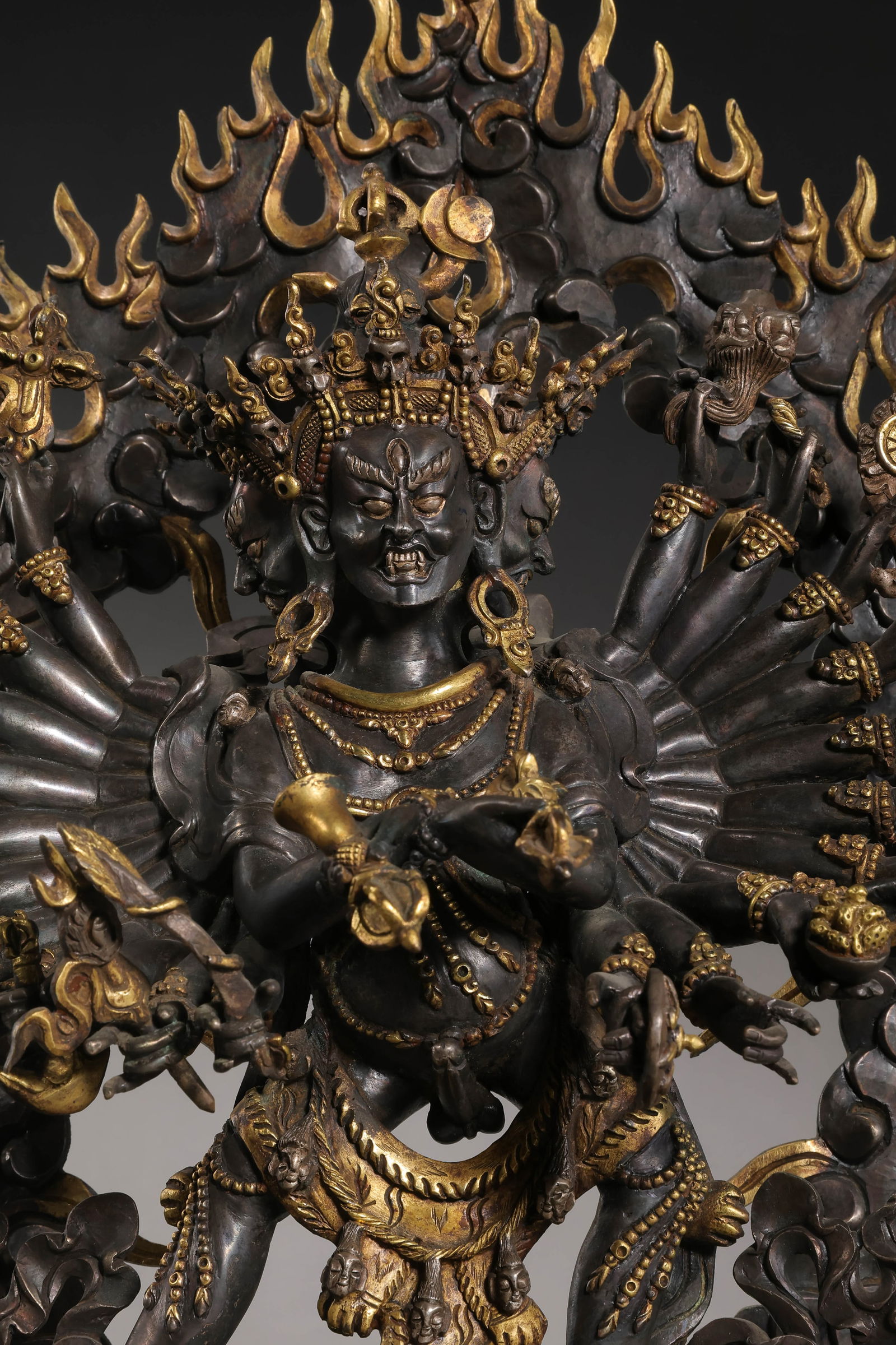 A RARE AND POWERFUL PARCEL-GILT BRONZE FIGURE OF A WRATHFUL VAJRA DEITYTIBET, 15TH – 16TH CENTURY: Description This formidable bronze figure depicts a wrathful deity—likely a manifestation of Vajrapani or a similar protector deity—standing in the dynamic pratyalidhasana (warrior) pose upon a lo