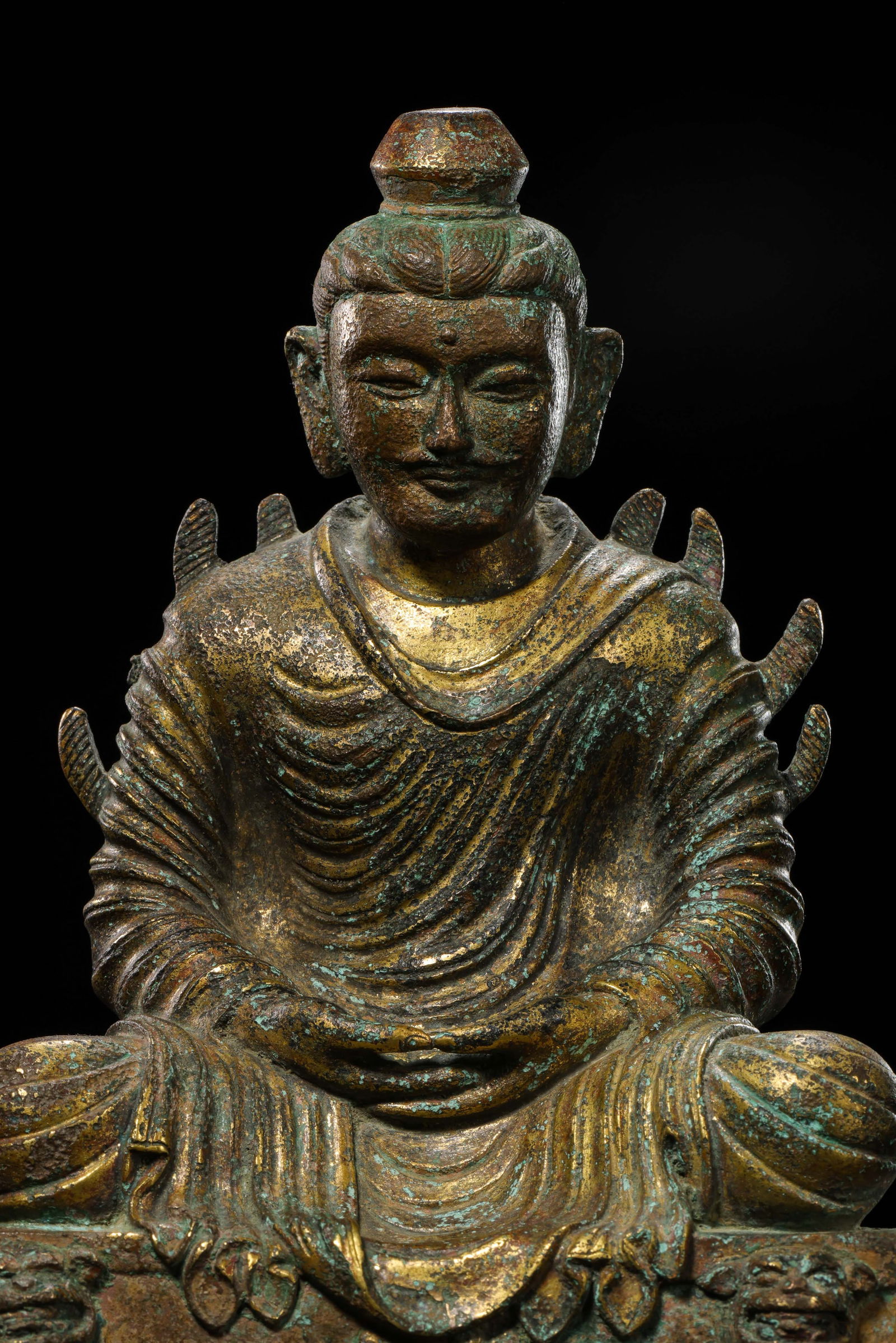 A RARE AND FINELY CAST GILT-BRONZE FIGURE OF A SEATED BUDDHAMING DYNASTY (1368-1644): Description The figure is masterfully cast seated in dhyanasana (meditative lotus position). The Buddha is depicted with a serene and dignified countenance, with downcast eyes and a subtle, enigmatic