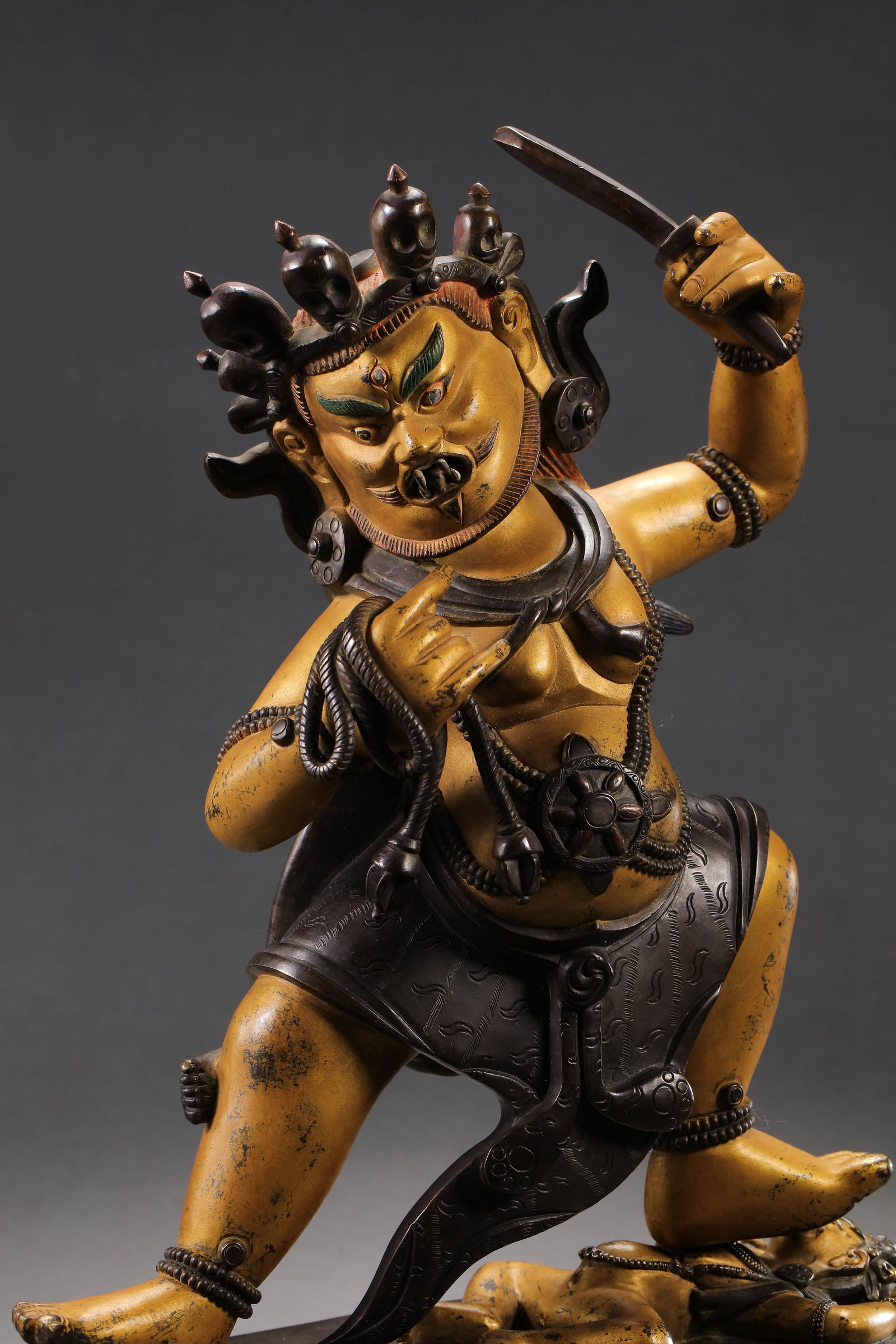 MAGNIFICENT AND POWERFULLY CAST IMPERIAL GILT-BRONZE FIGURE OF A WRATHFUL DEITY, POSSIBLY: DescriptionThe deity is masterfully modeled with an imposing, muscular physique, depicted standing in a dynamic alidhasana (stepping) pose on a lotus pedestal. The fierce countenance is expertly rende